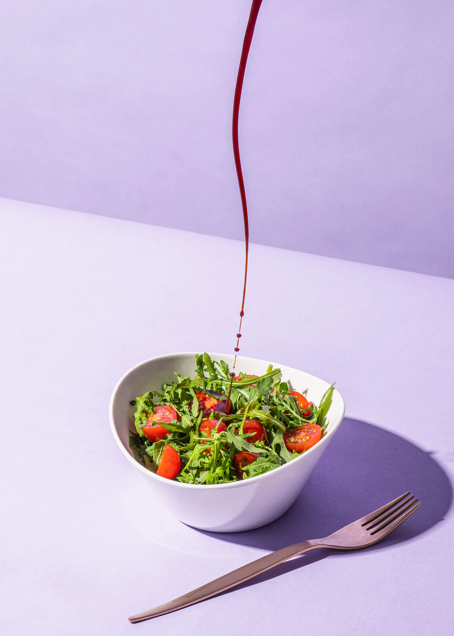 Eine Schüssel Salat mit Tomaten und Salatblättern wird mit Soße bestrichen