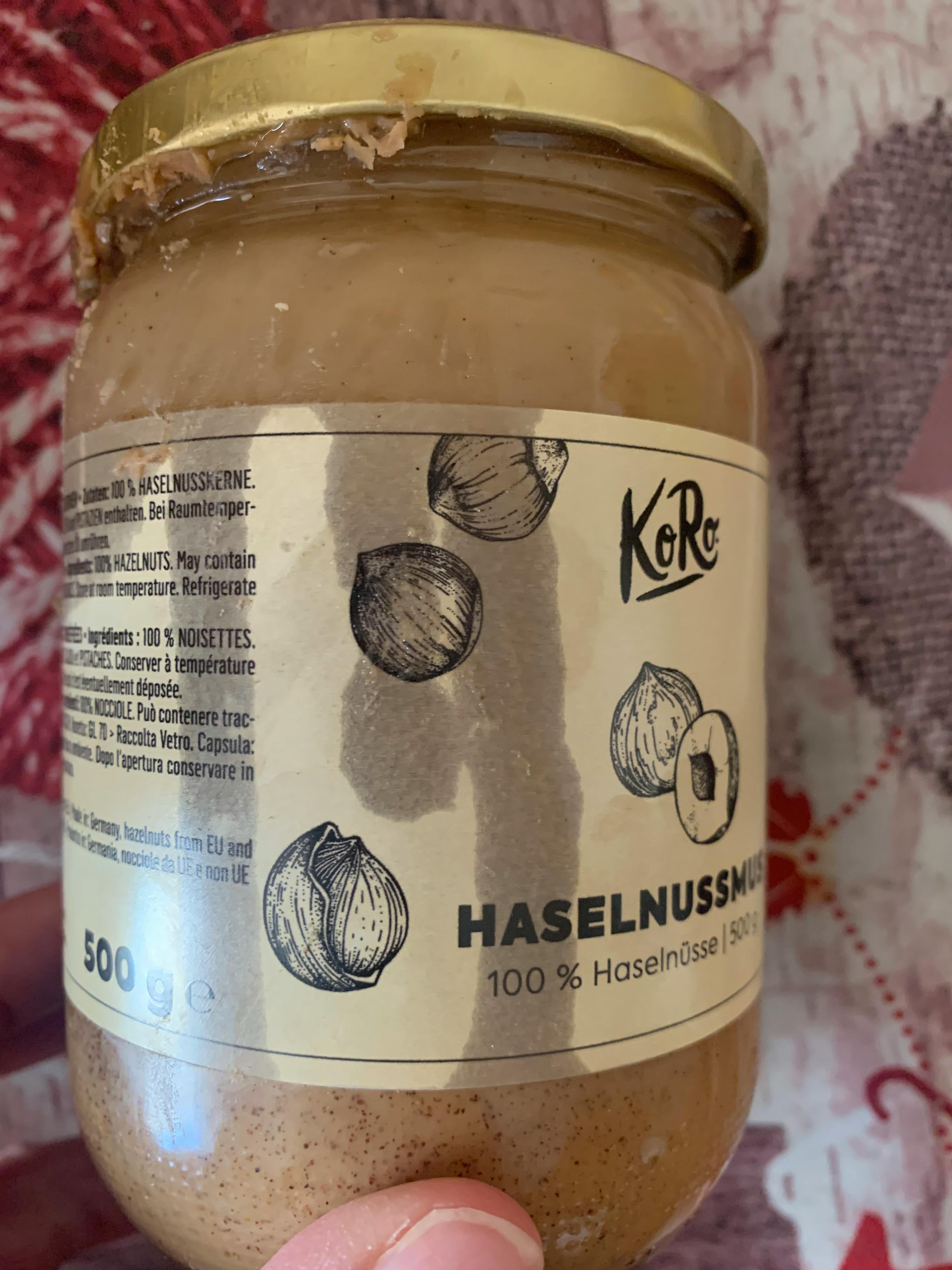 eine Person hält ein Glas Haselnussmus mit einem Bild von Haselnüssen darauf