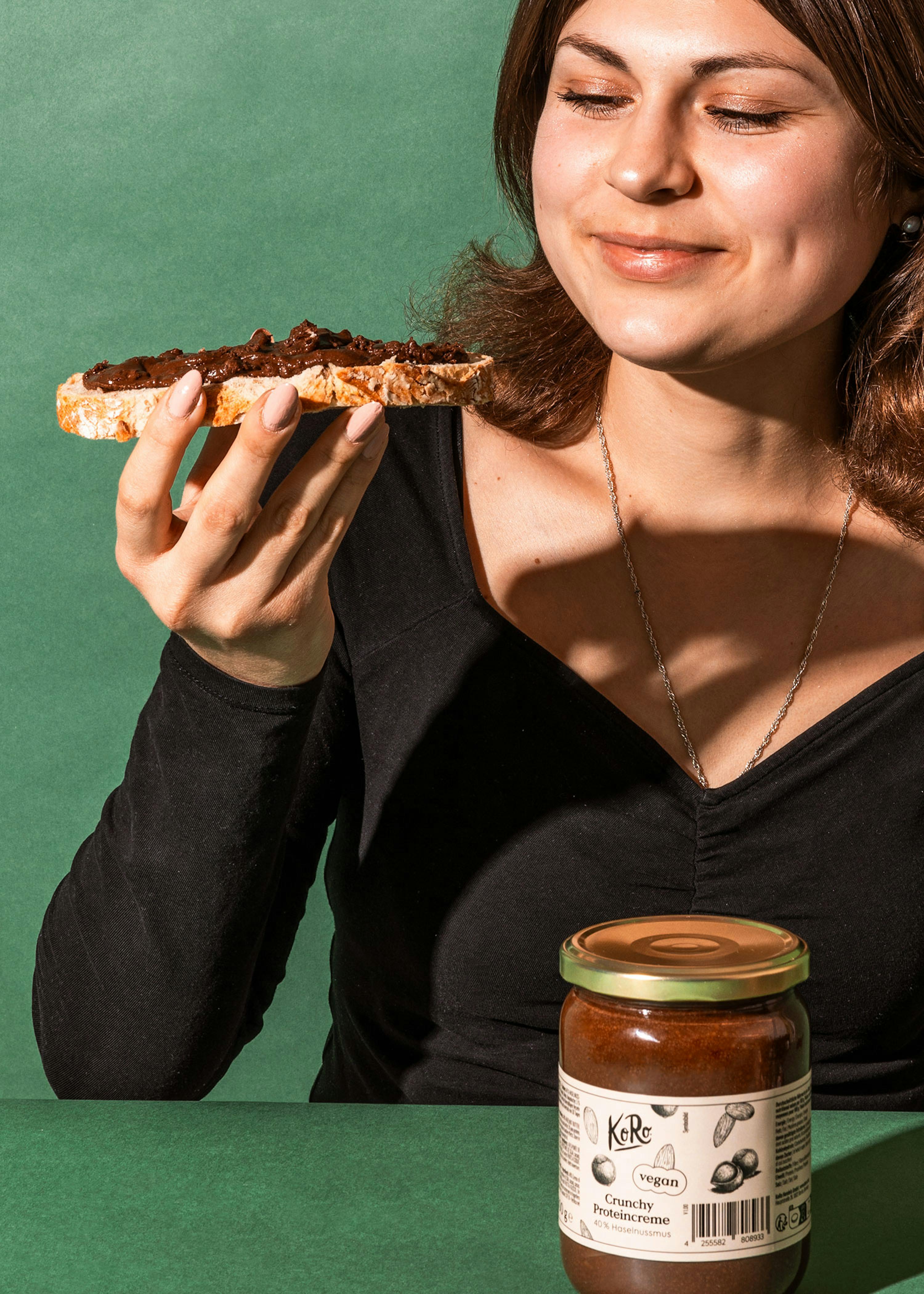 a woman holding a slice of bread next to a jar of kerr peanut butter