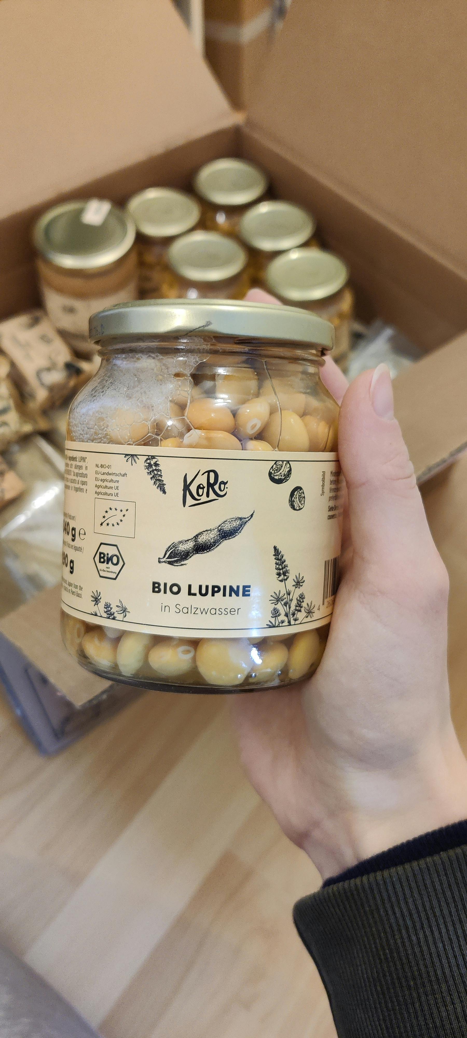 une personne tient un bocal en verre de lupin bio