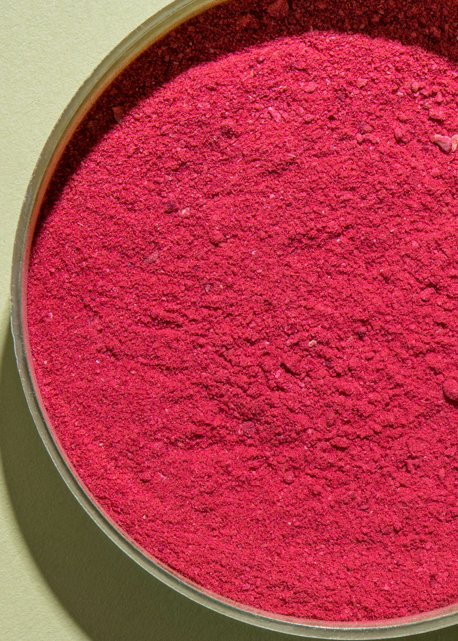 un gros plan d' un bol de poudre rose sur fond vert