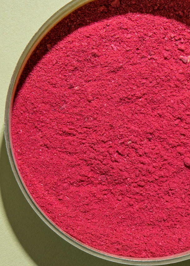 un gros plan d' un bol de poudre rose sur fond vert