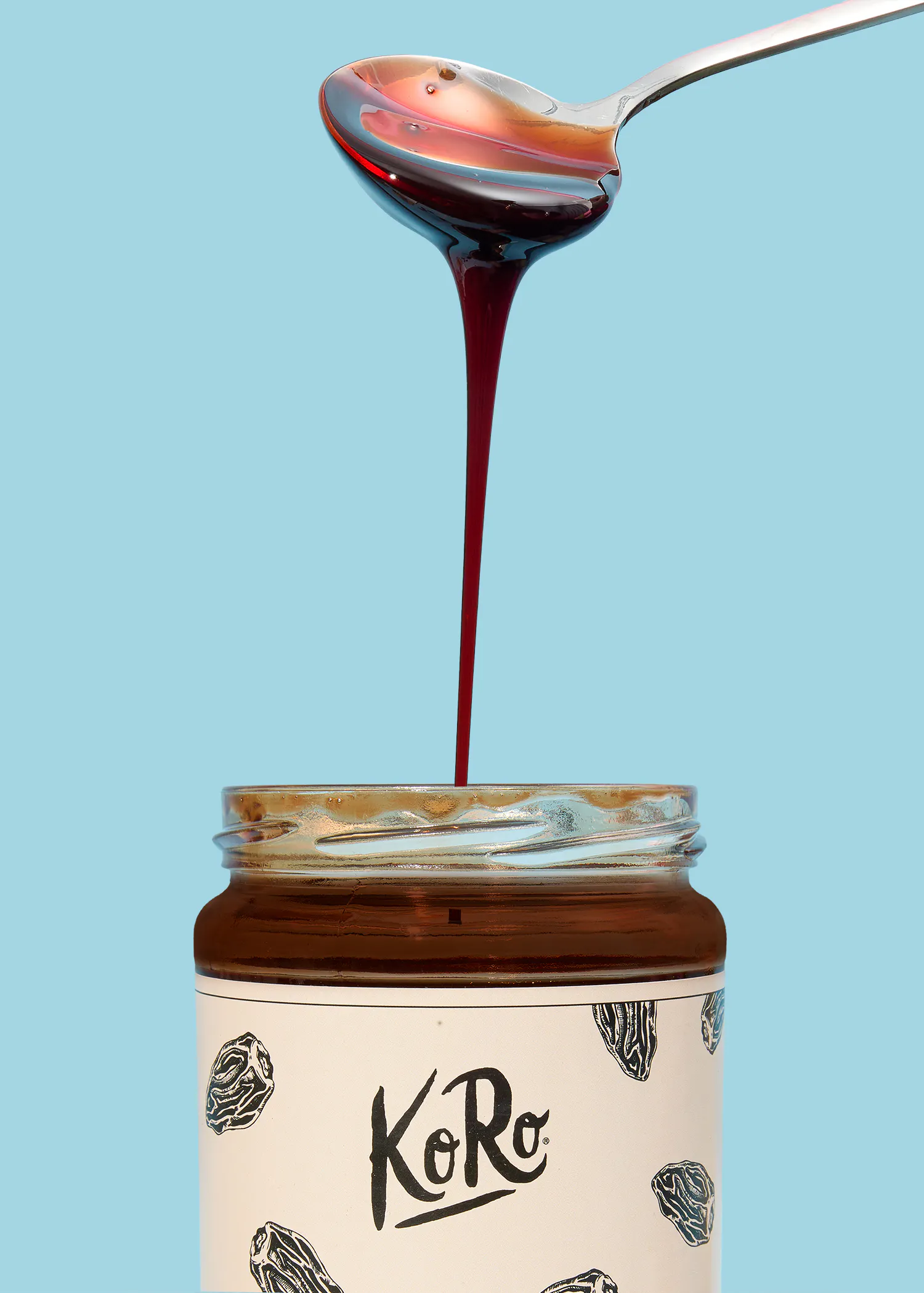 une cuillère verse du sirop sur une bouteille avec le logo koro
