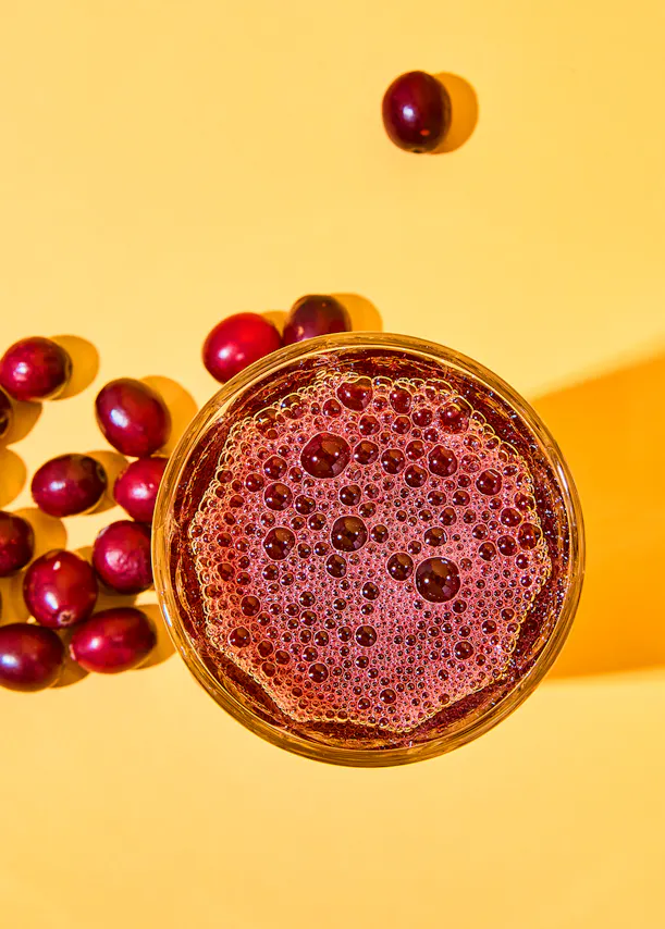 a glass of cranberry juice is surrounded by cranberries
