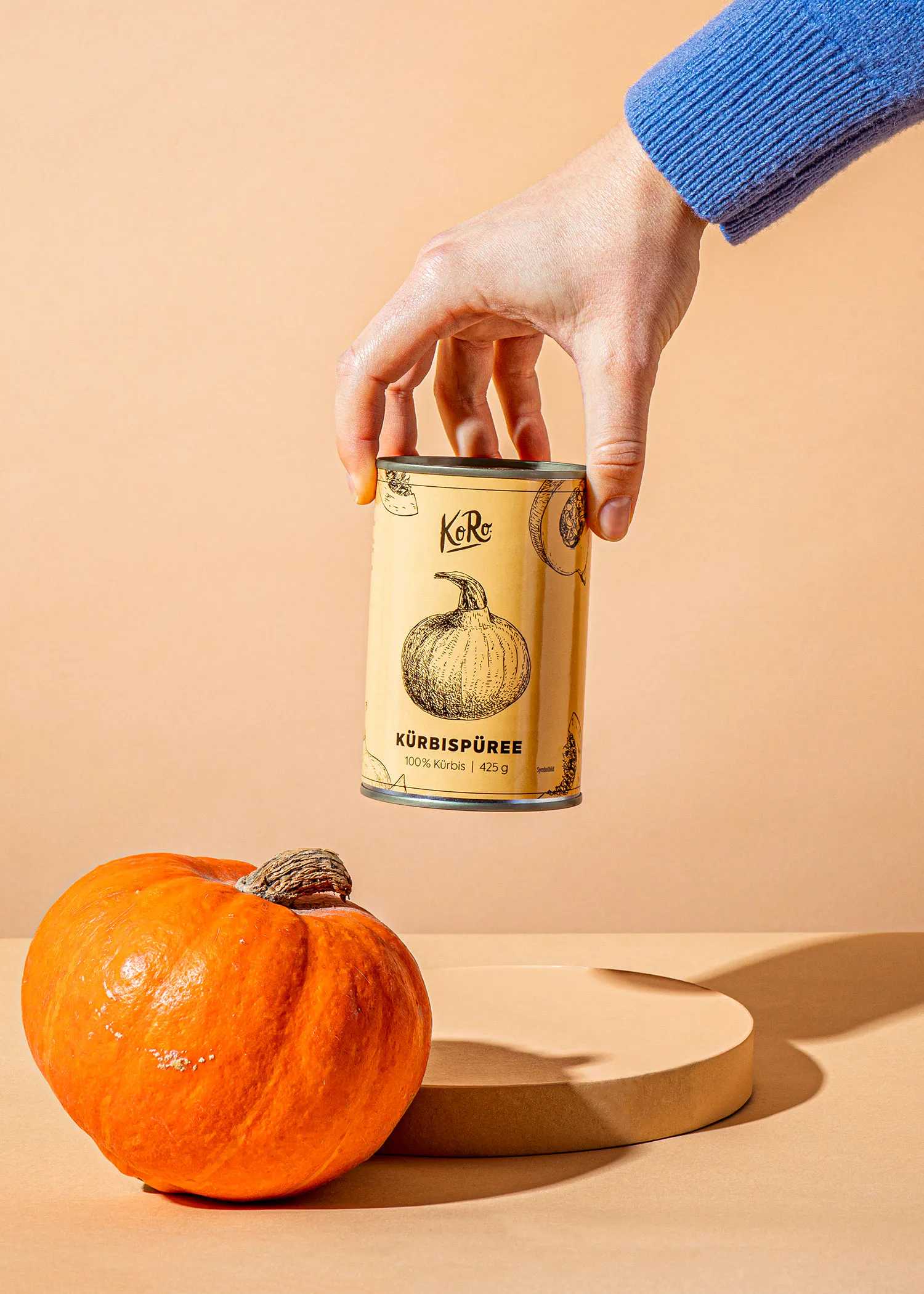 une personne tient une canette de purée de citrouille à côté d' une citrouille