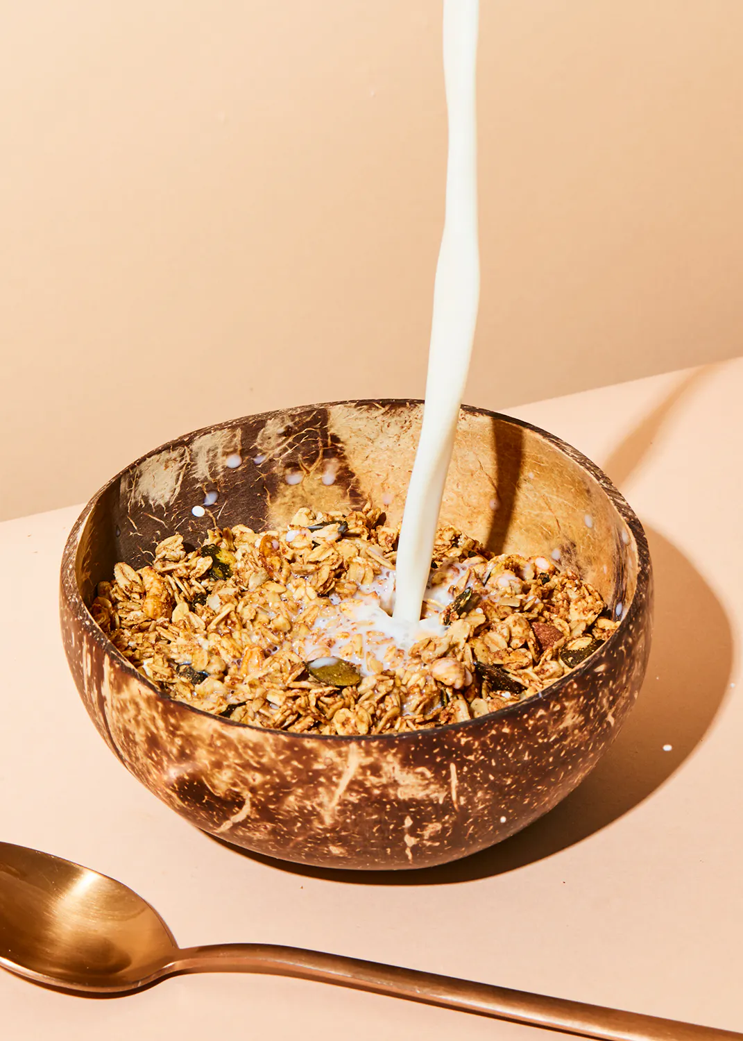 un bol en bois rempli de granola et de lait avec une cuillère