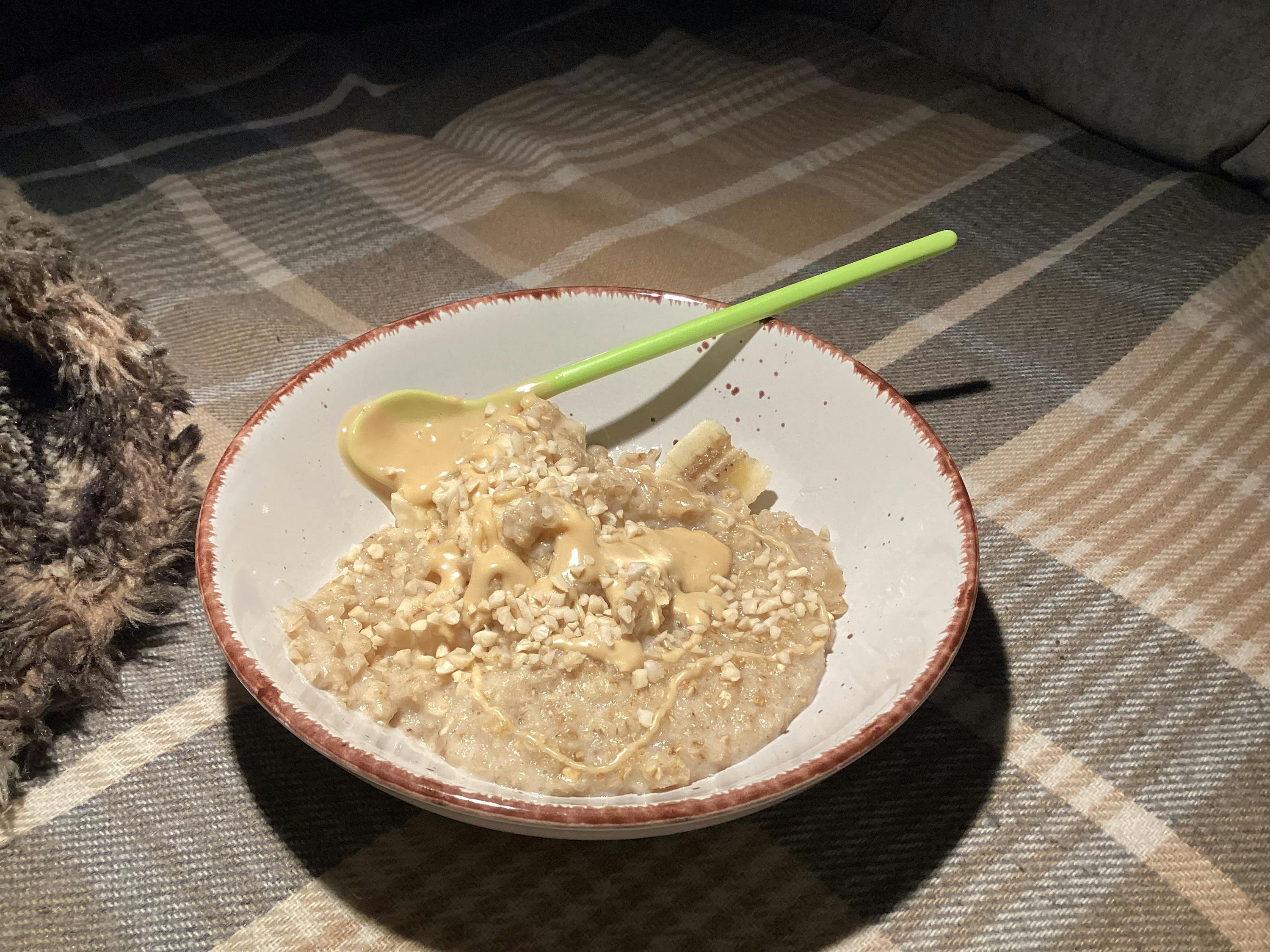 eine Schüssel Haferflocken mit Bananen und Erdnussbutter und einem Löffel