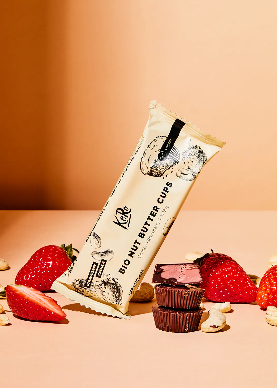 un paquet de tasses au beurre de cacahuète bio est posé sur une table avec des fraises et du chocolat