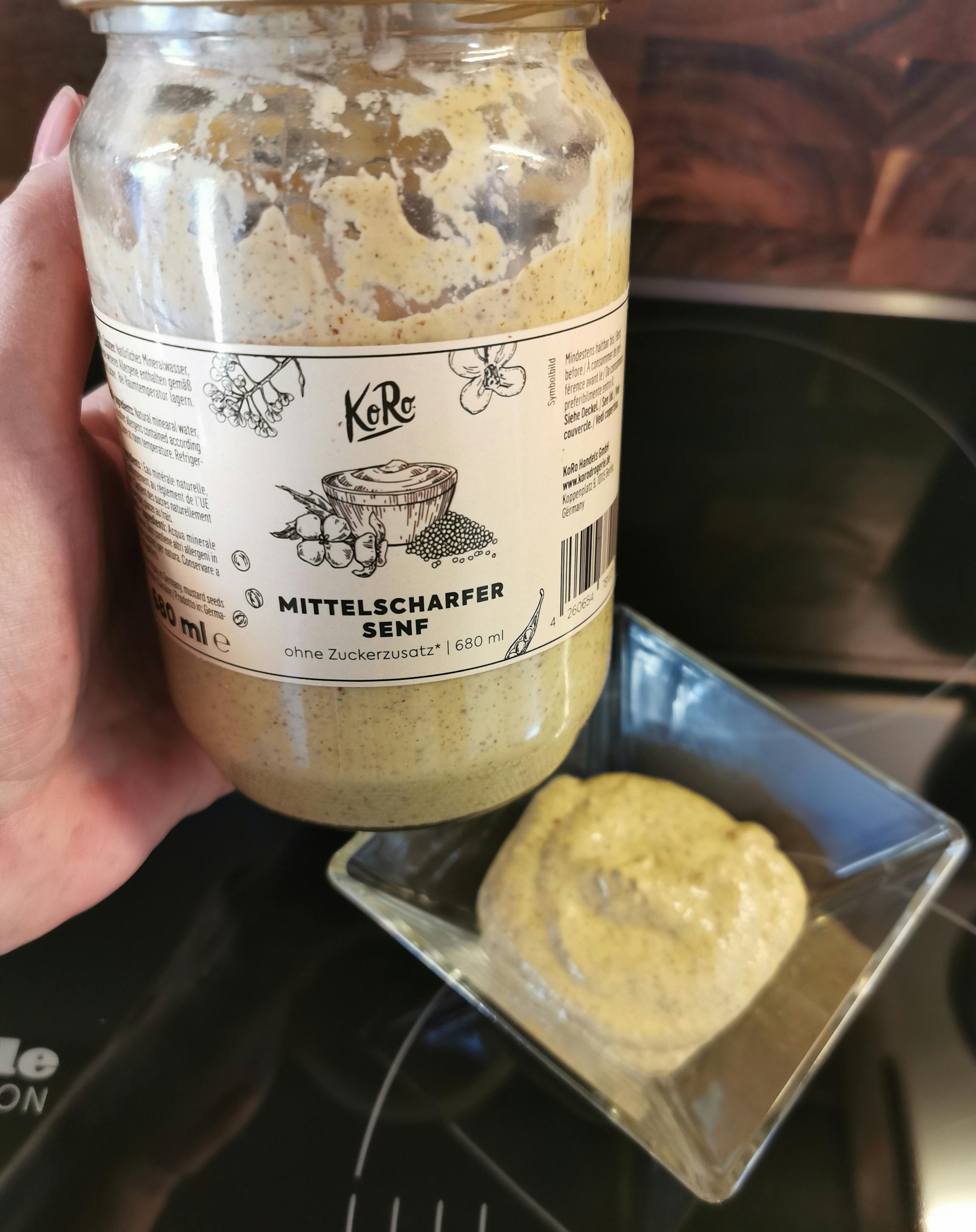 une personne tient un bocal de sauce à l' huile de sésame à côté d' un bol de sauce