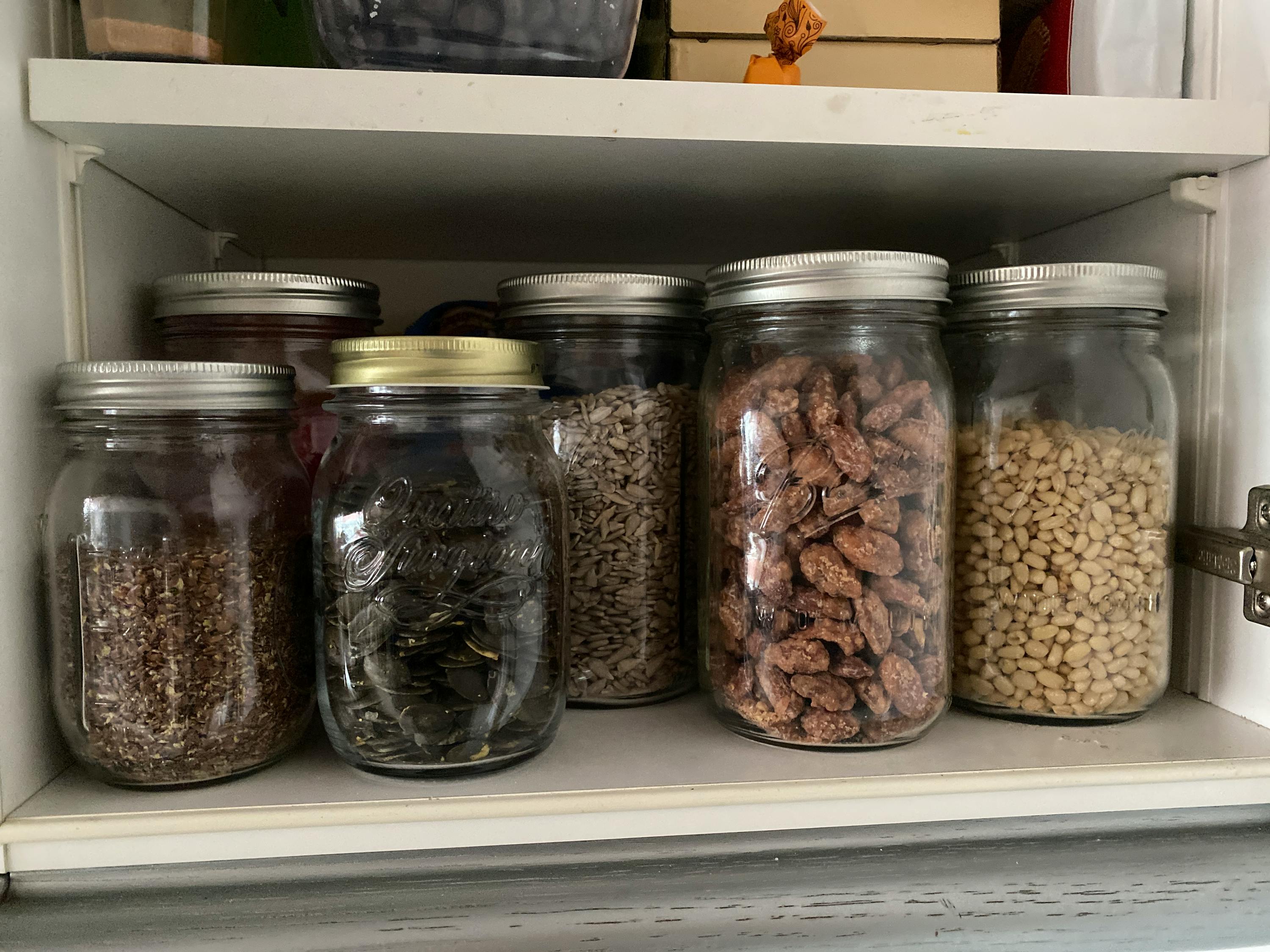 a mason jar filled with nuts and seeds sits on a shelf