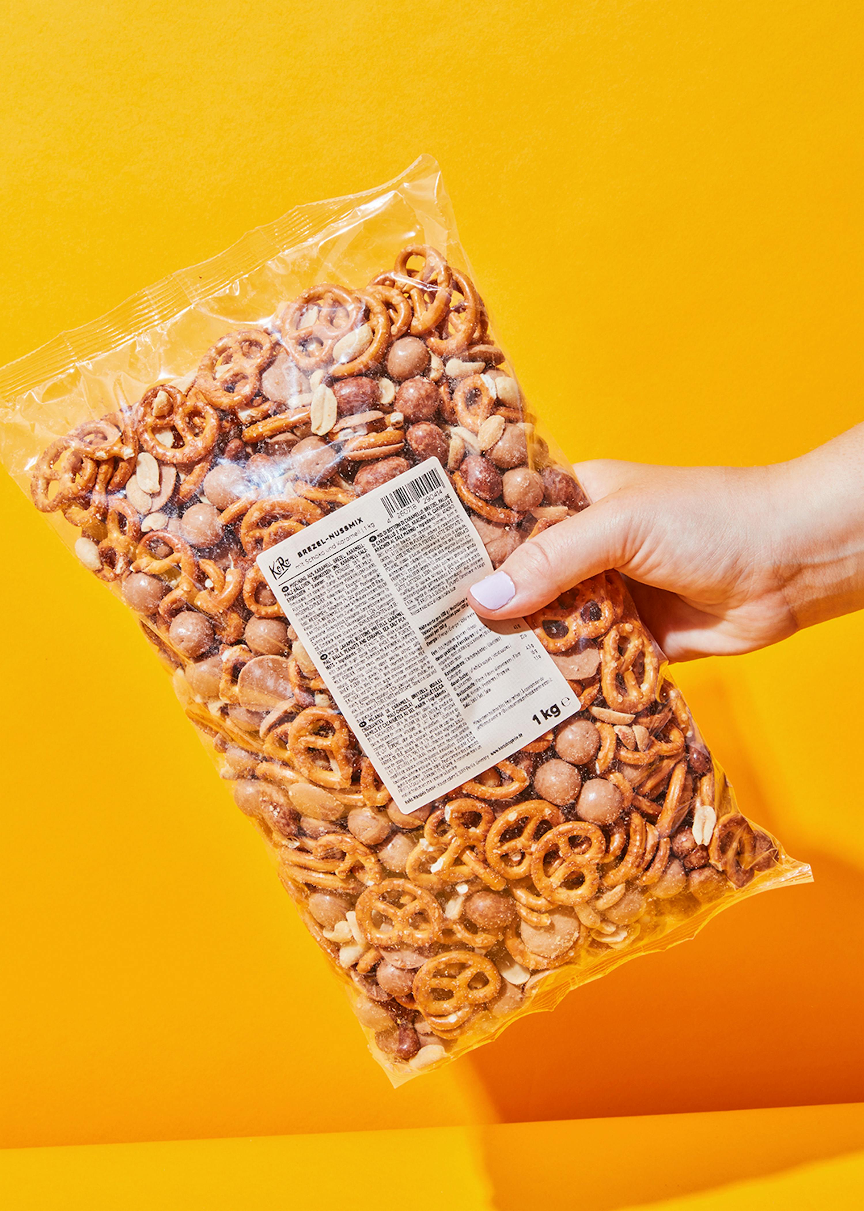 une personne tient un sac de bretzels et d' arachides