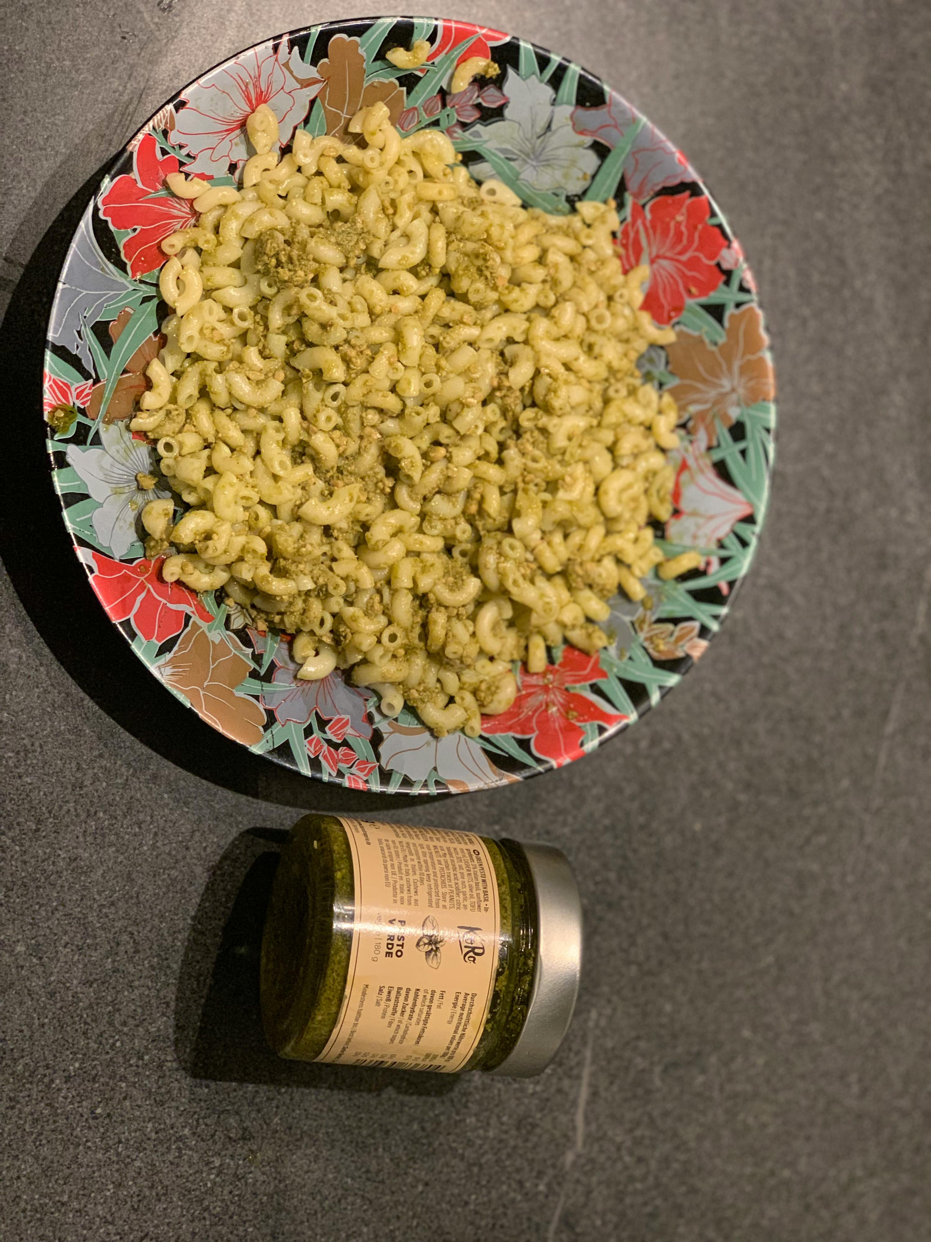 eine Flasche pesto steht neben einem Teller mit Nudeln