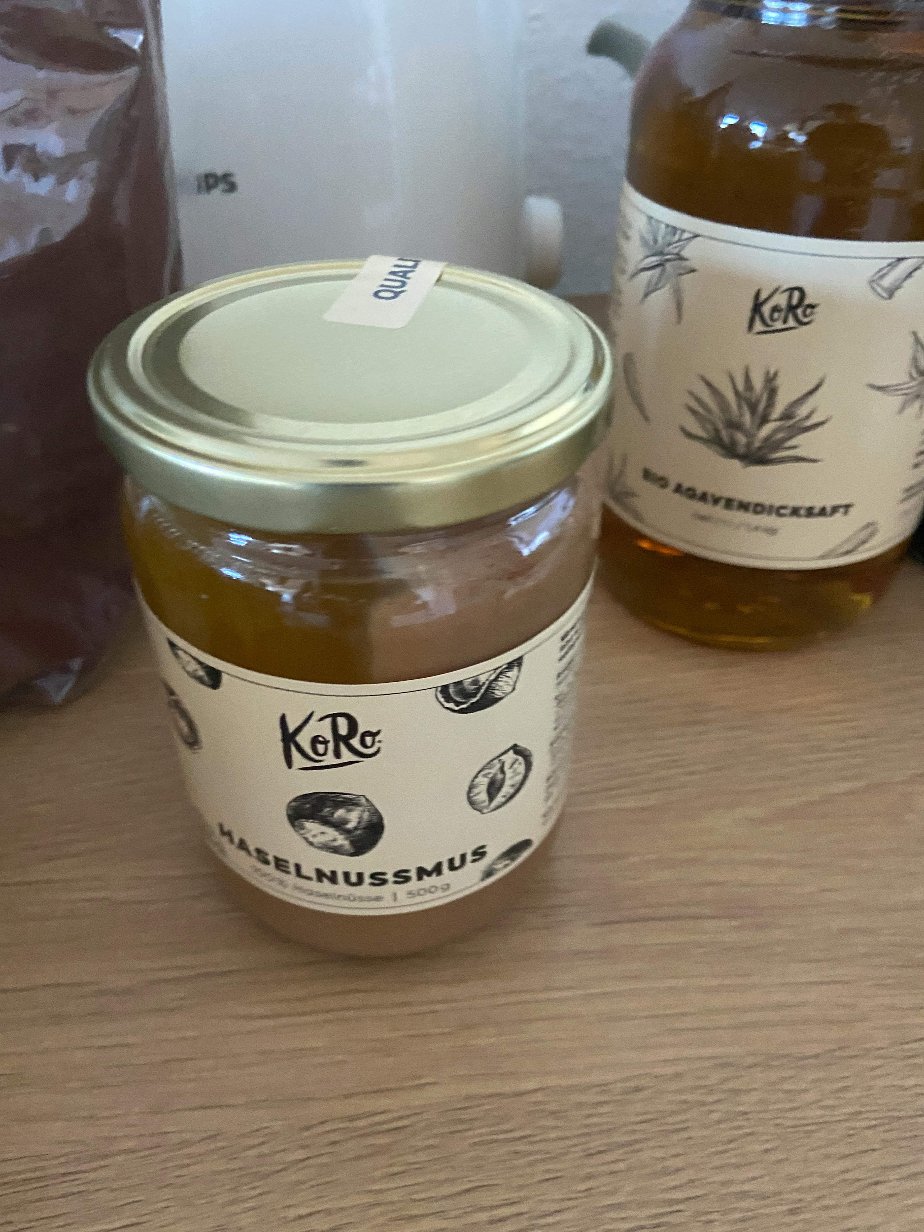 two jars of hazelnussmus sit on a wooden table