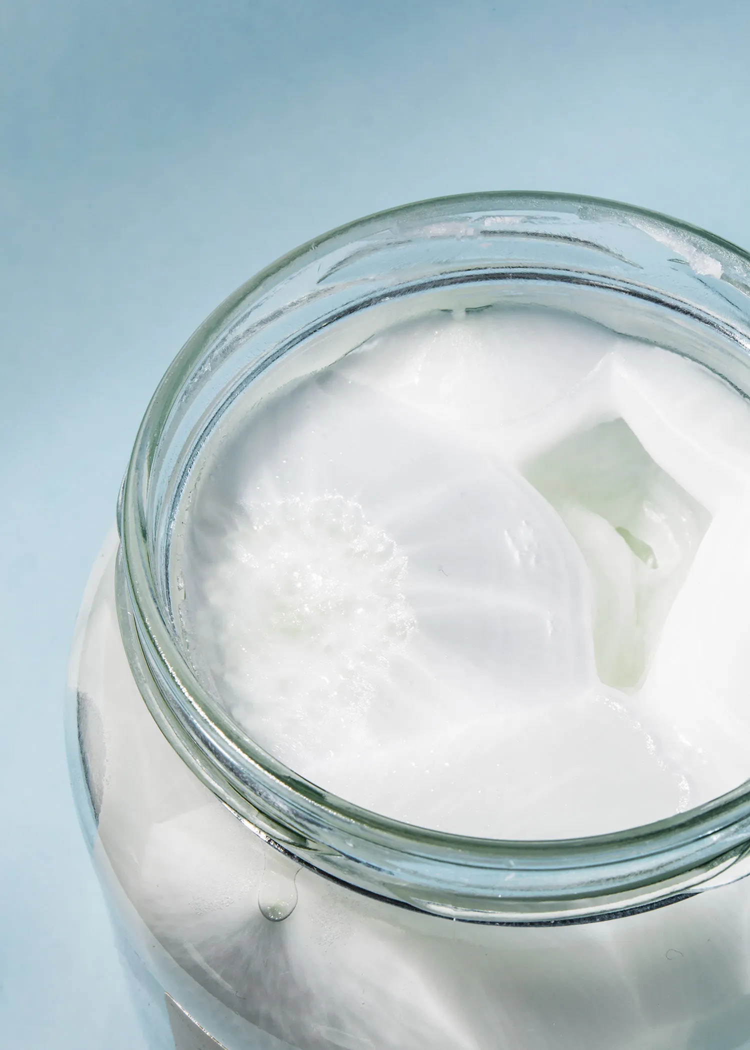 a glass jar filled with white liquid on a blue surface