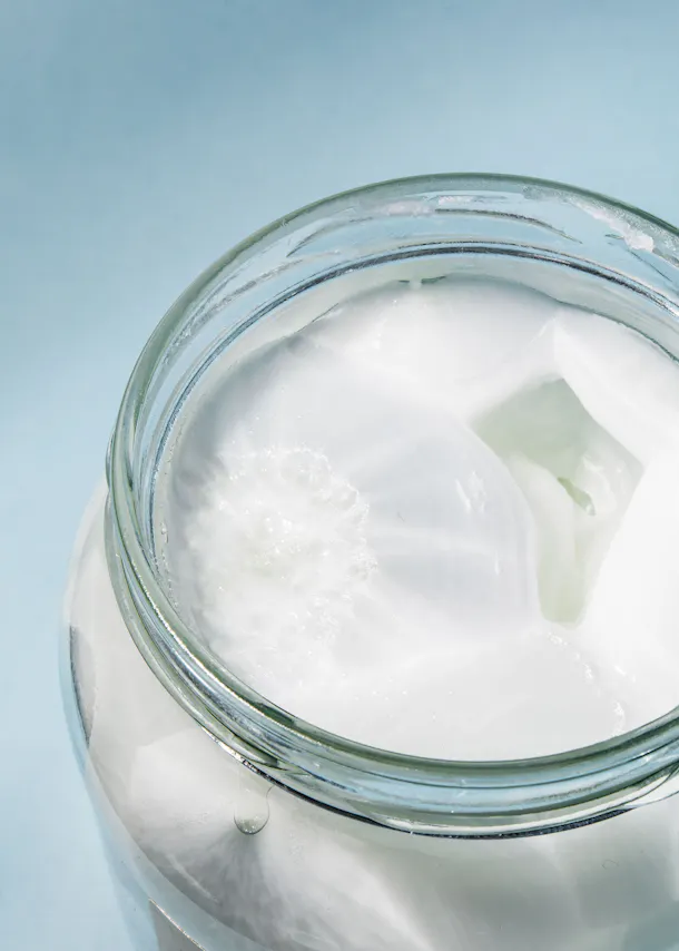 a glass jar filled with white liquid on a blue surface