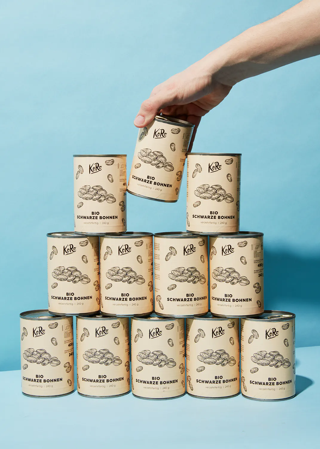 a hand is reaching for a can of bio schwarze bohnen