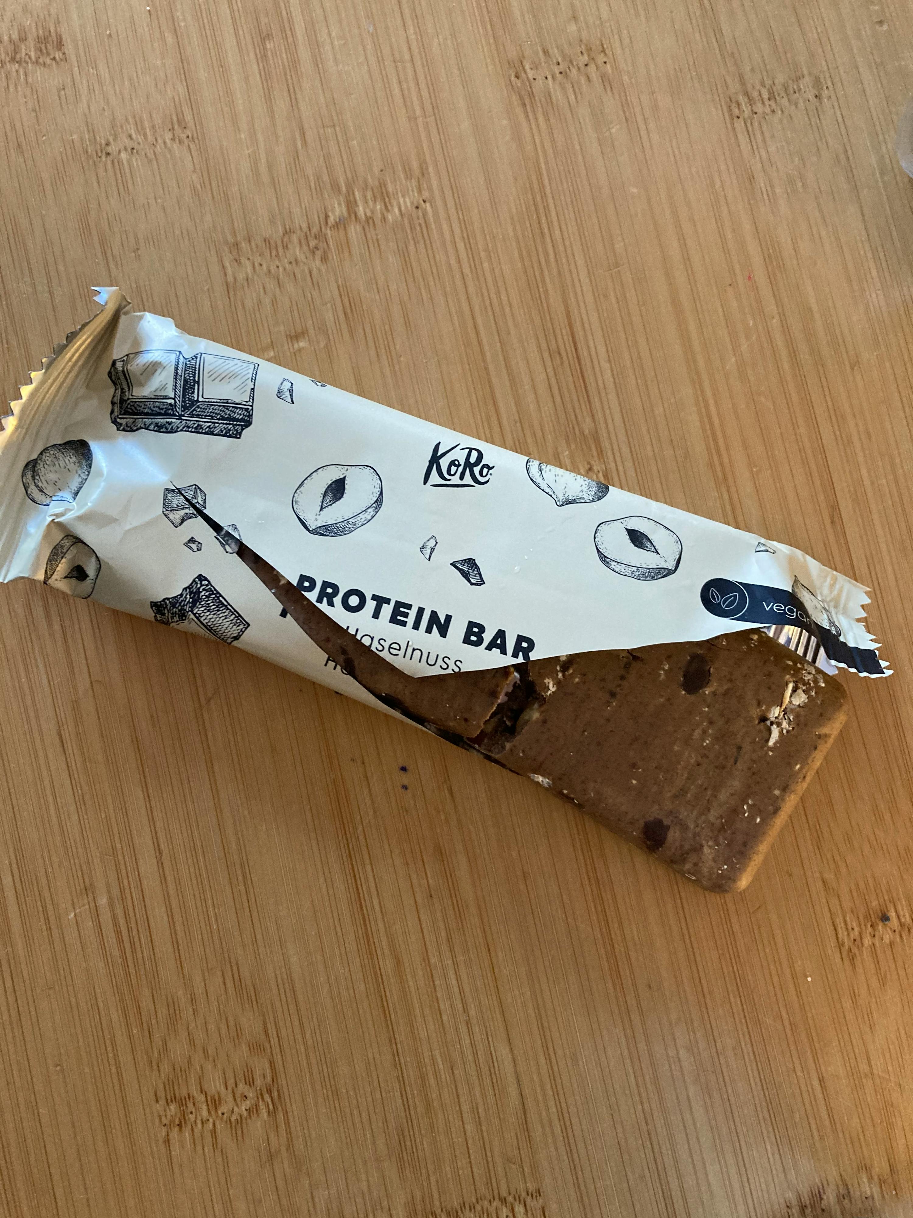 eine proteinbar mit haselnuss und schokolade liegt auf einem holztisch
