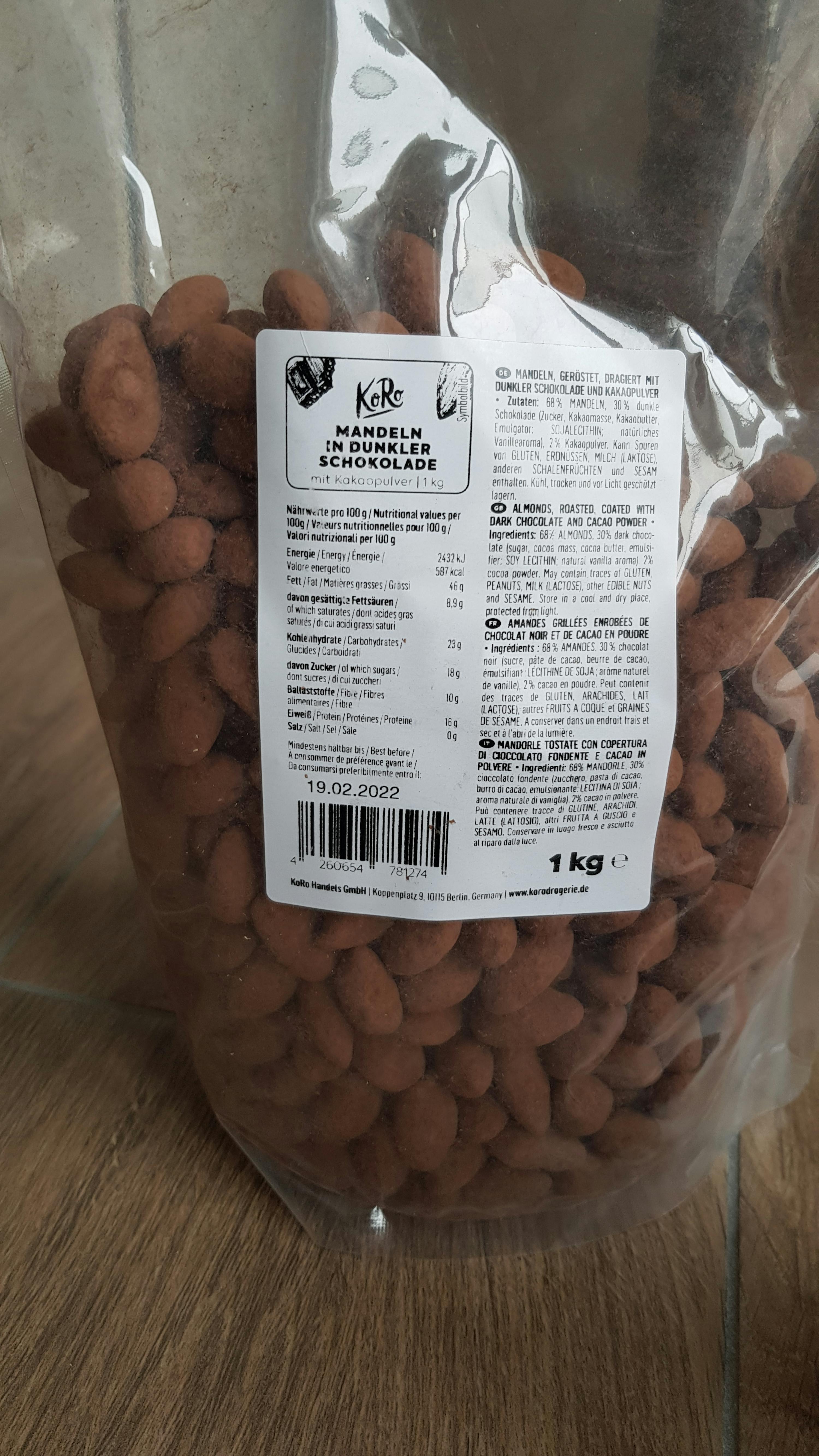 ein Plastikbeutel mit mandeln in Schokolade liegt auf einem Holztisch