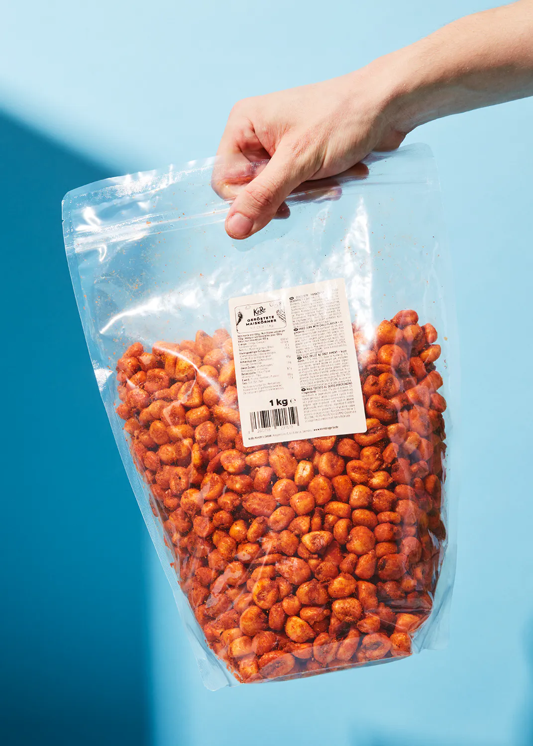 une personne tient un sac de cacahuètes avec une étiquette qui dit 1 kg