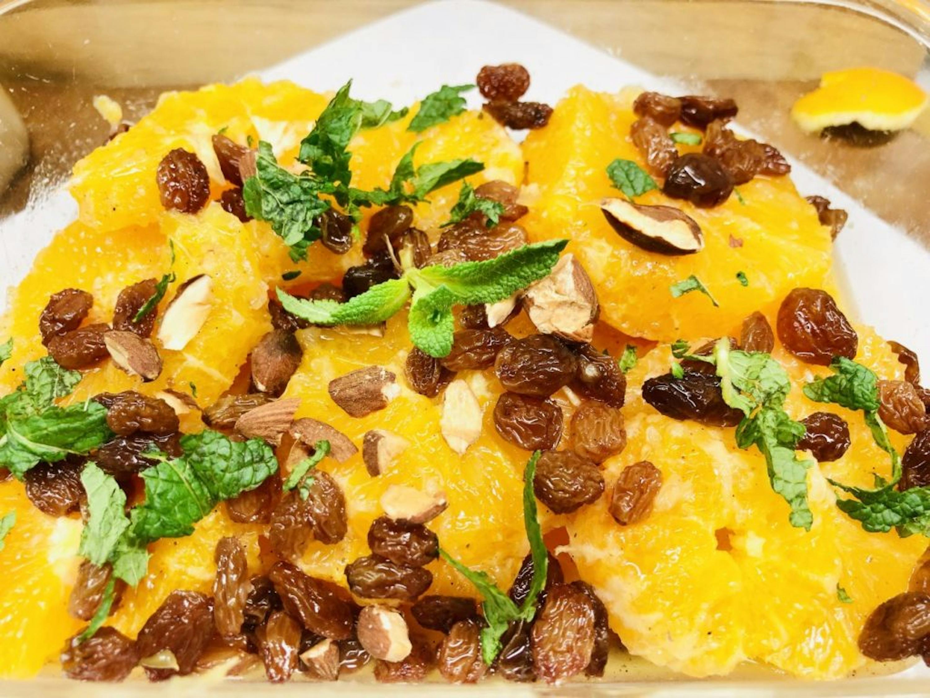 une assiette en verre remplie d' oranges , de raisins secs et de menthe