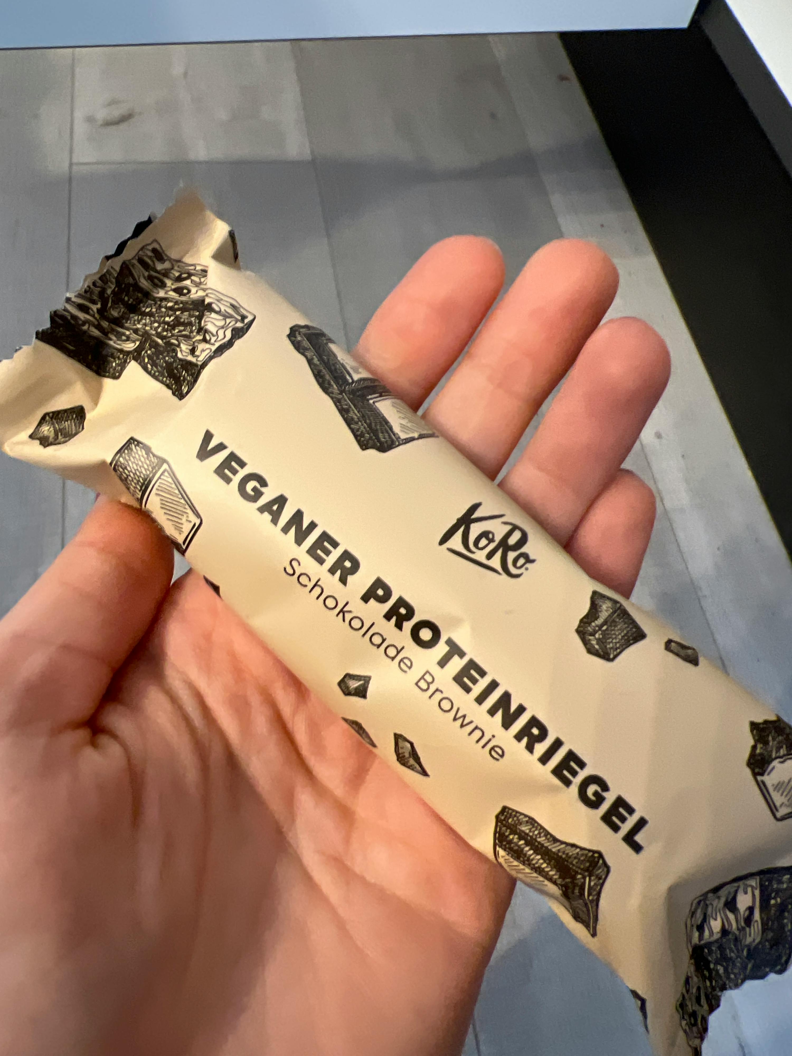 a hand is holding a veganer proteinriegel chocolate brownie