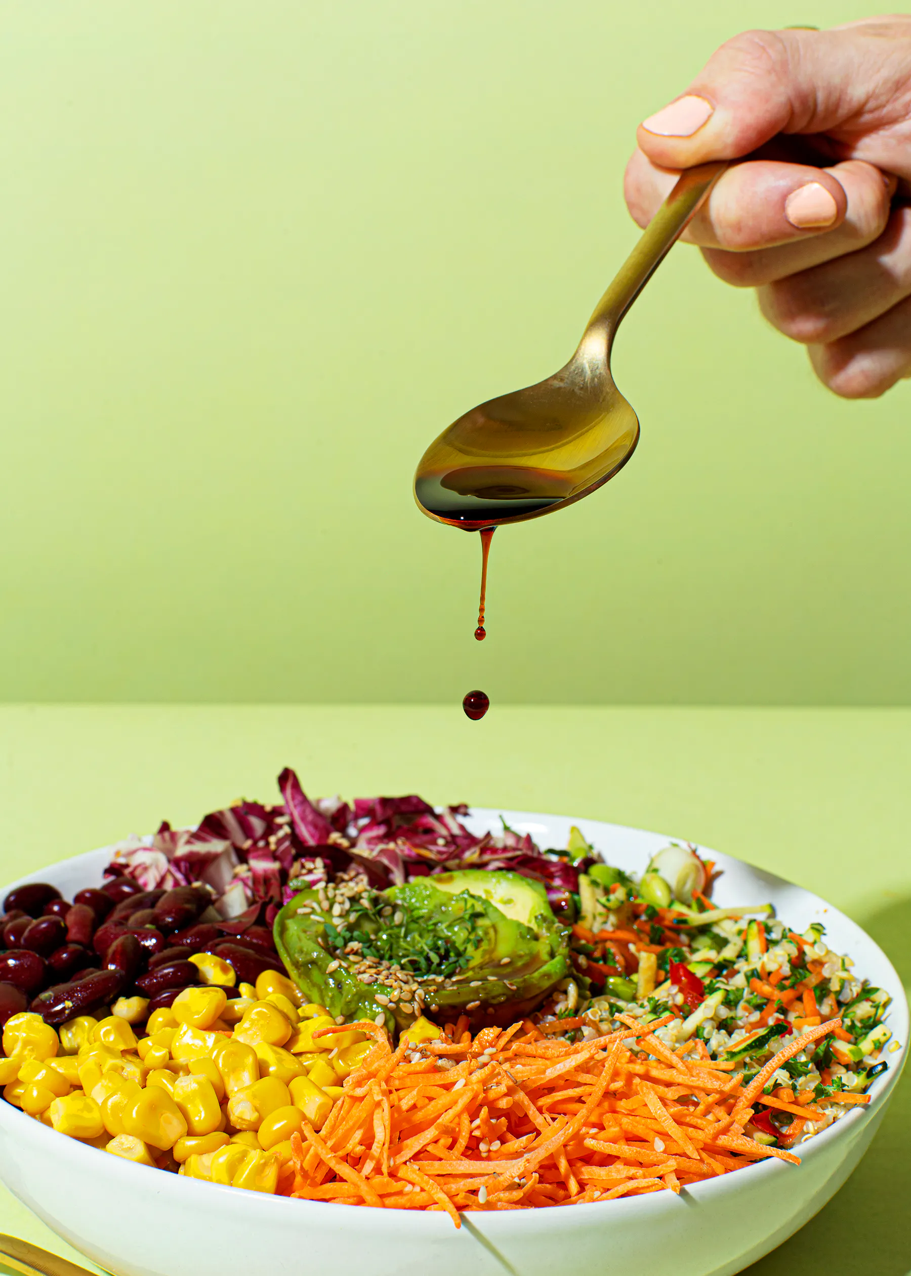 a person is pouring sauce into a bowl of salad
