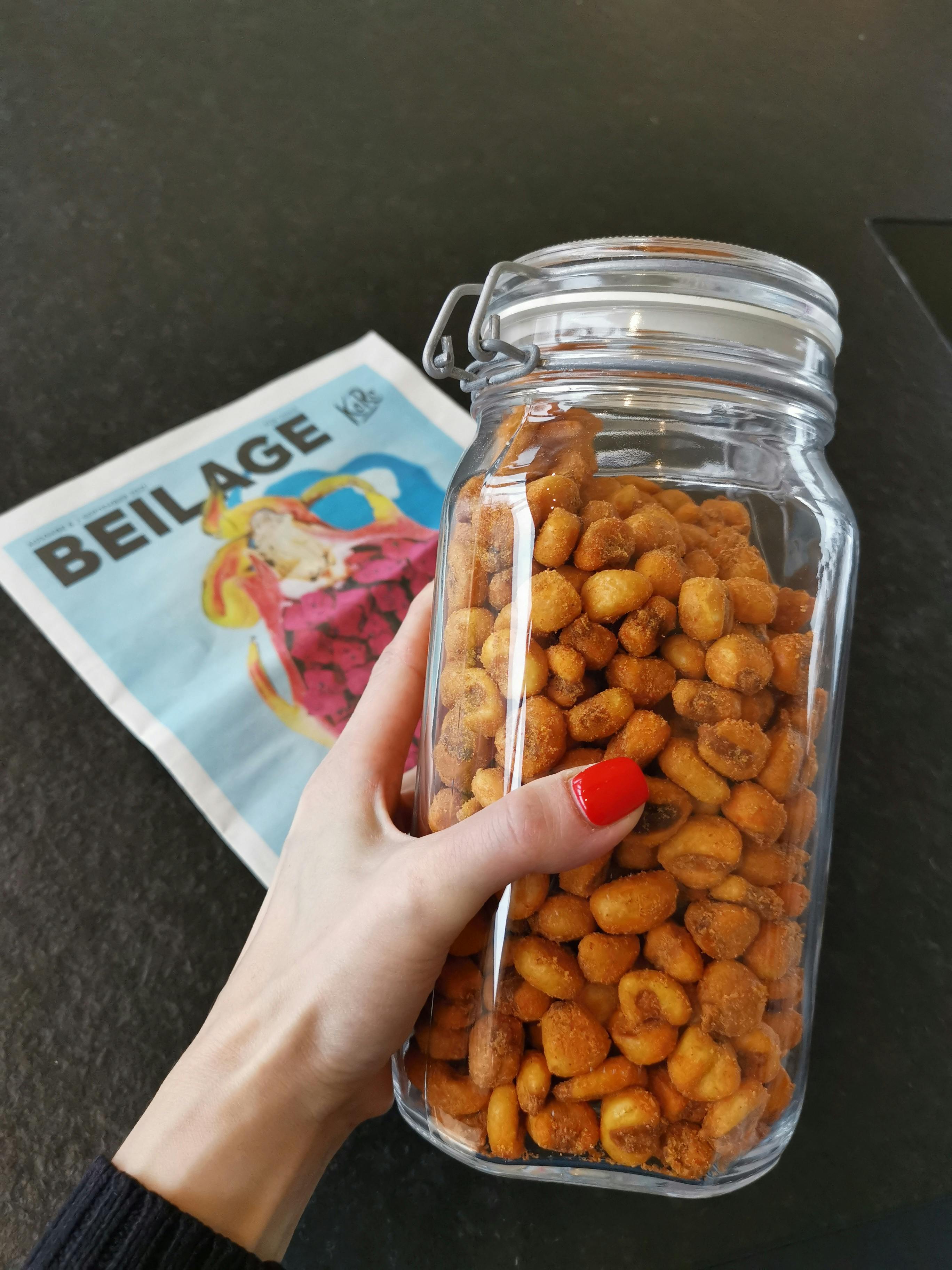 une personne tient un bocal rempli de nourriture à côté d' un journal avec beilage écrit dessus