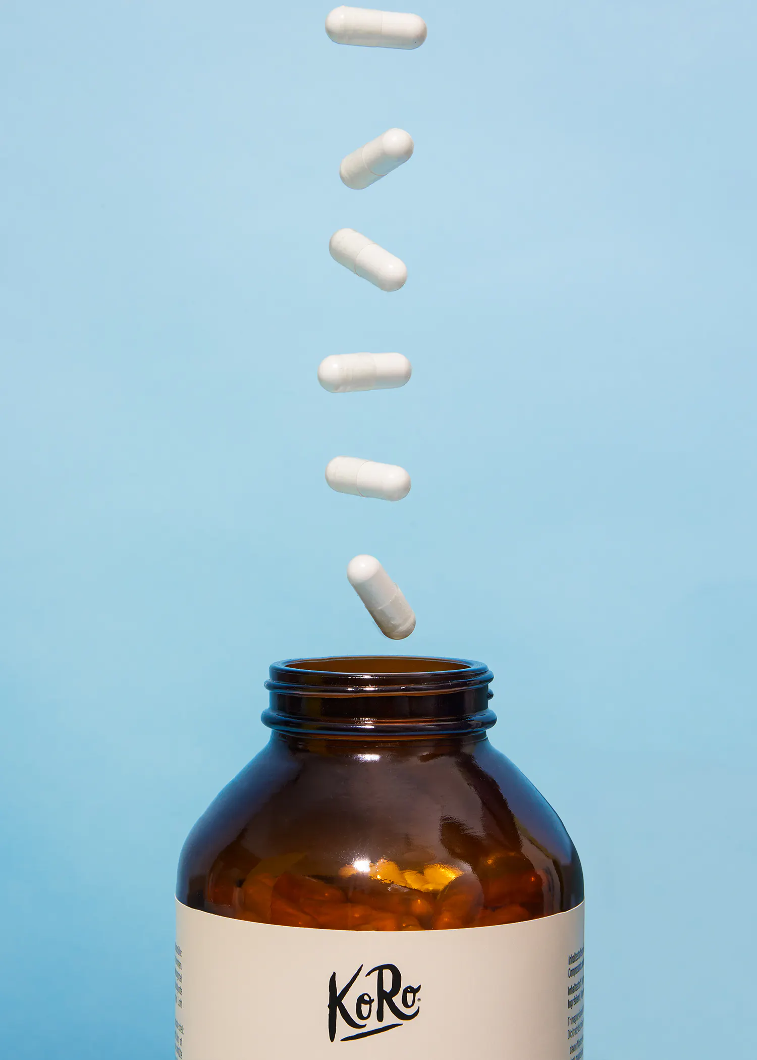 a bottle of koro pills with capsules falling out of it