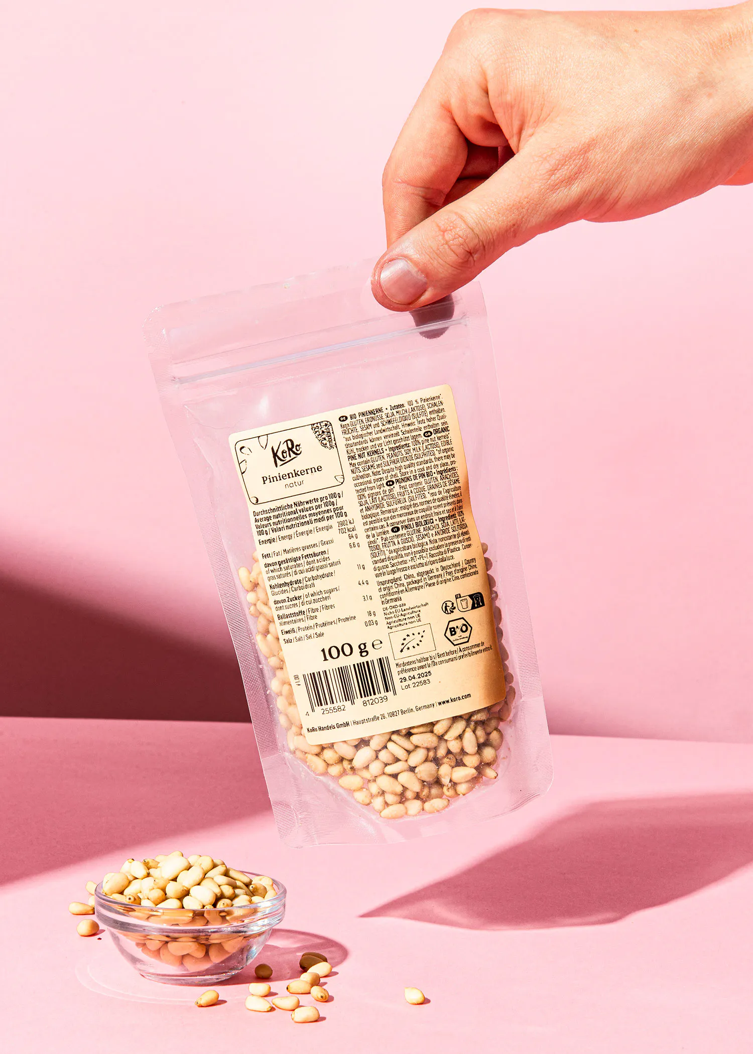 una persona sostiene un paquete de piñones en una mesa rosa