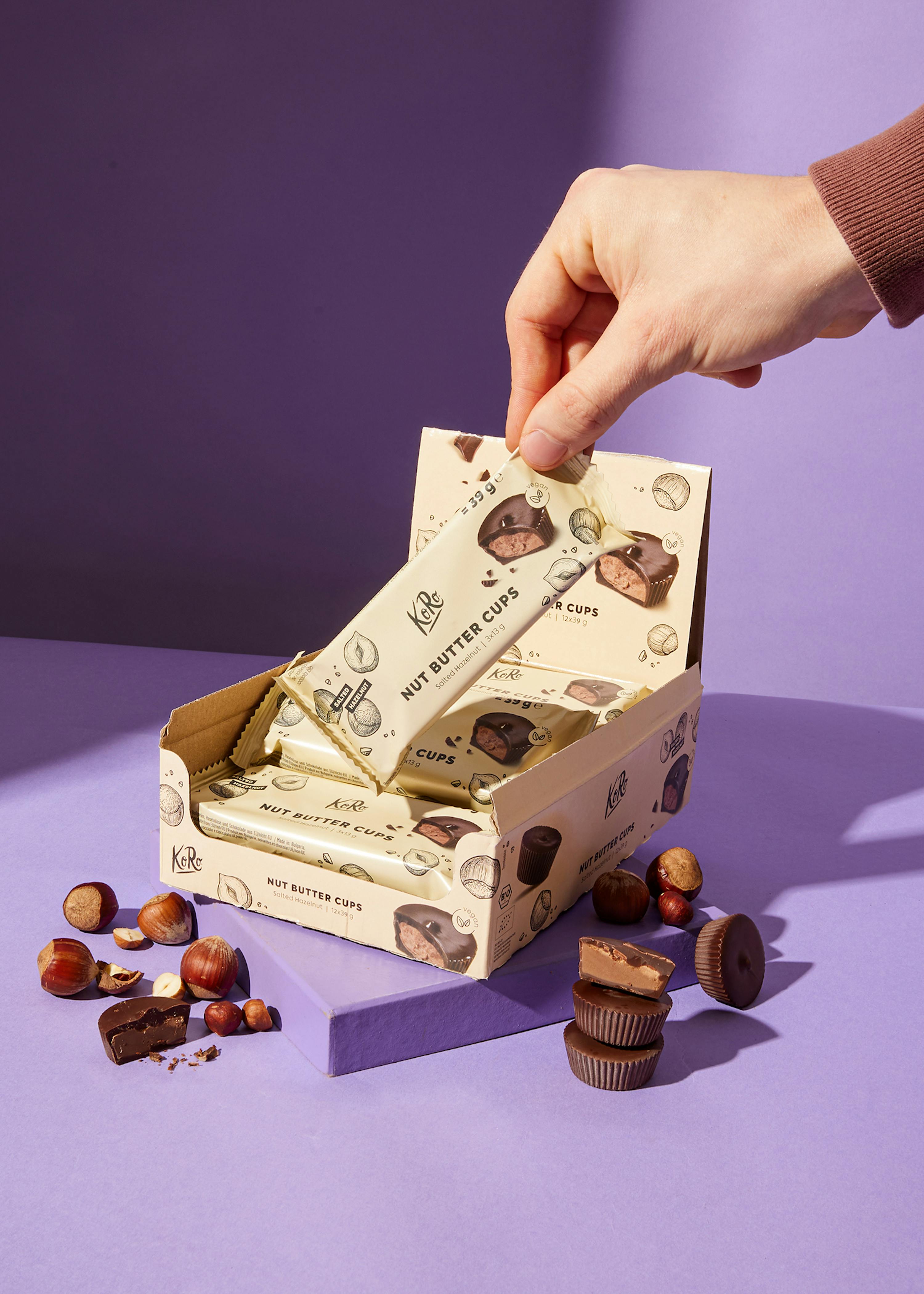 Eine Person nimmt einen Stück Schokolade aus einer Schachtel mit Kirschnussbuttercups