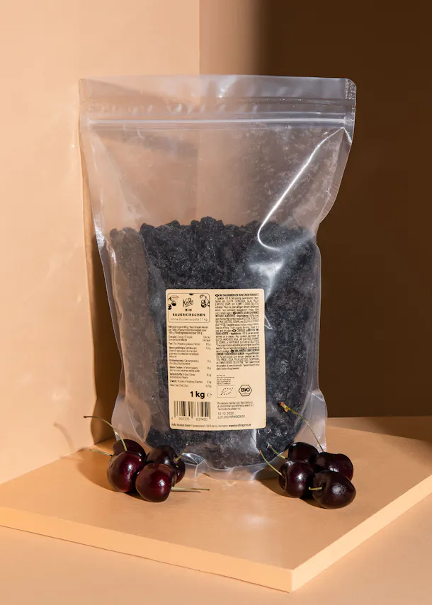 a bag of dried cherries sits on a table next to some cherries