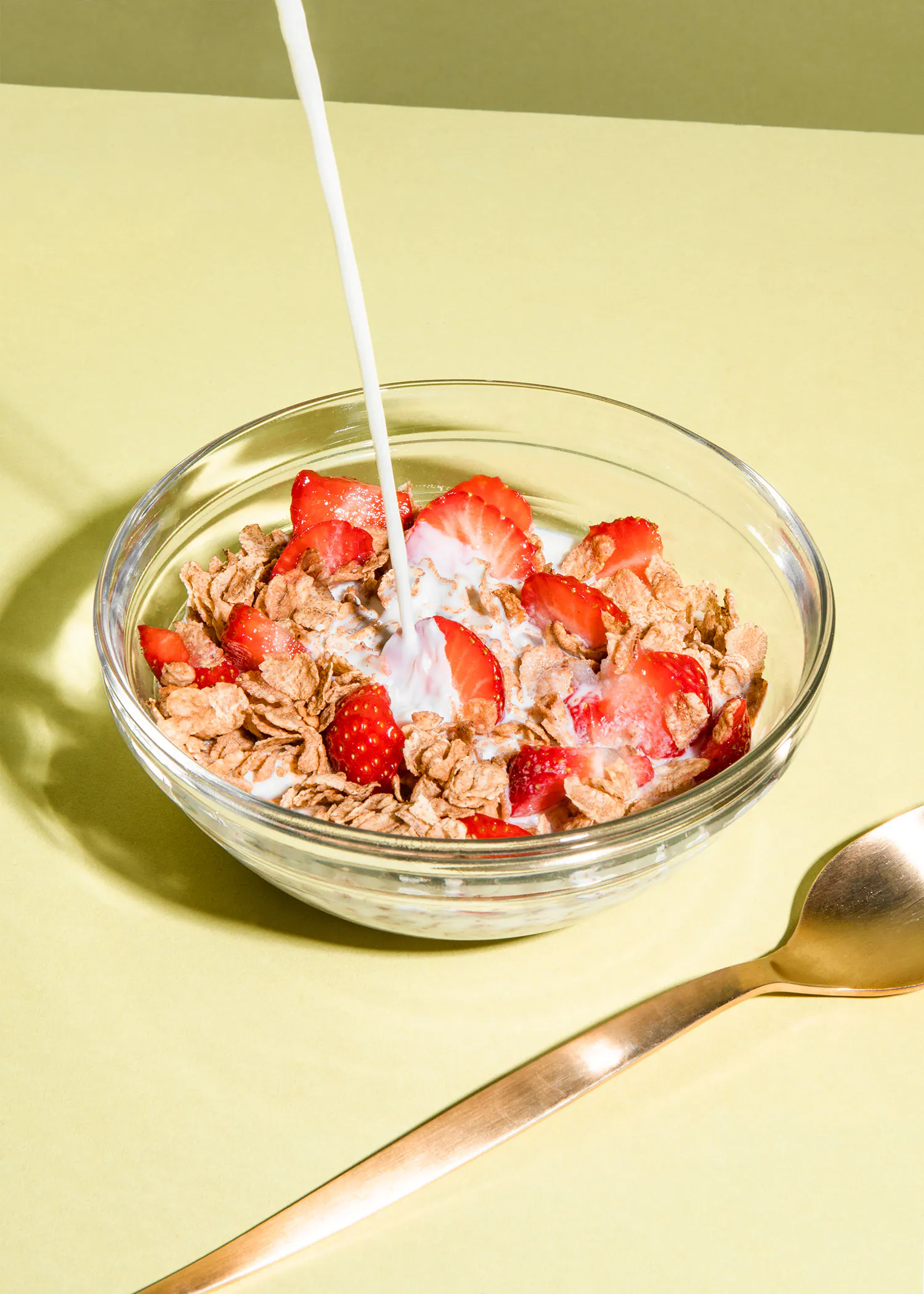 un bol de céréales avec des fraises et du lait et une cuillère