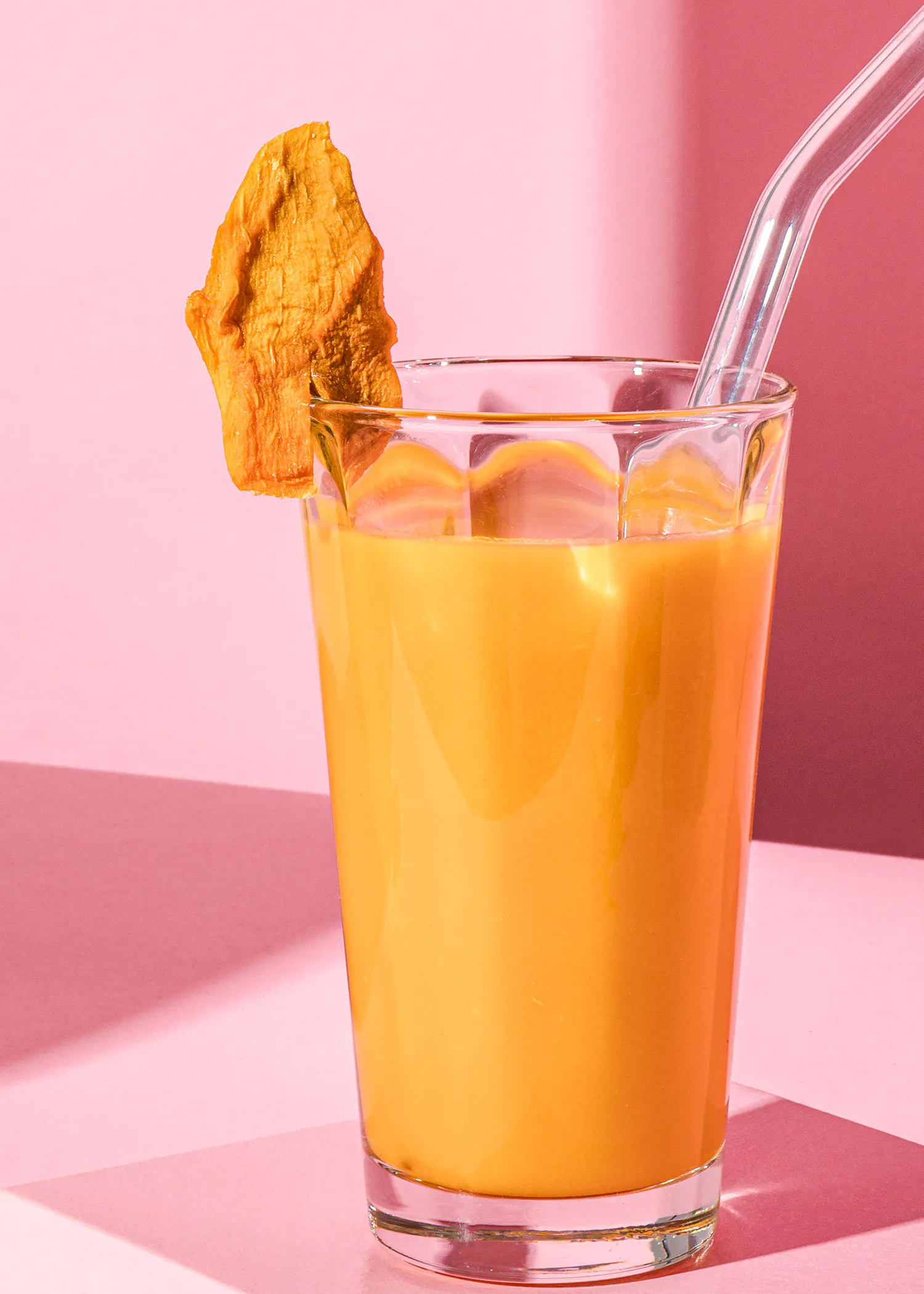 un verre de boisson avec une paille et une tranche de fruit