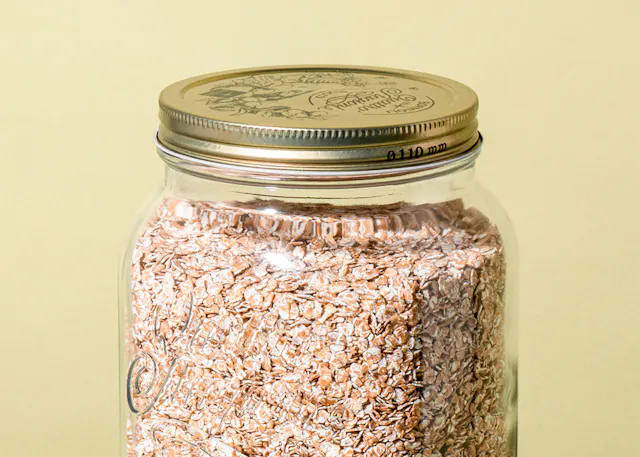 ein Glasgefäß mit Haferflocken und einem goldenen Deckel