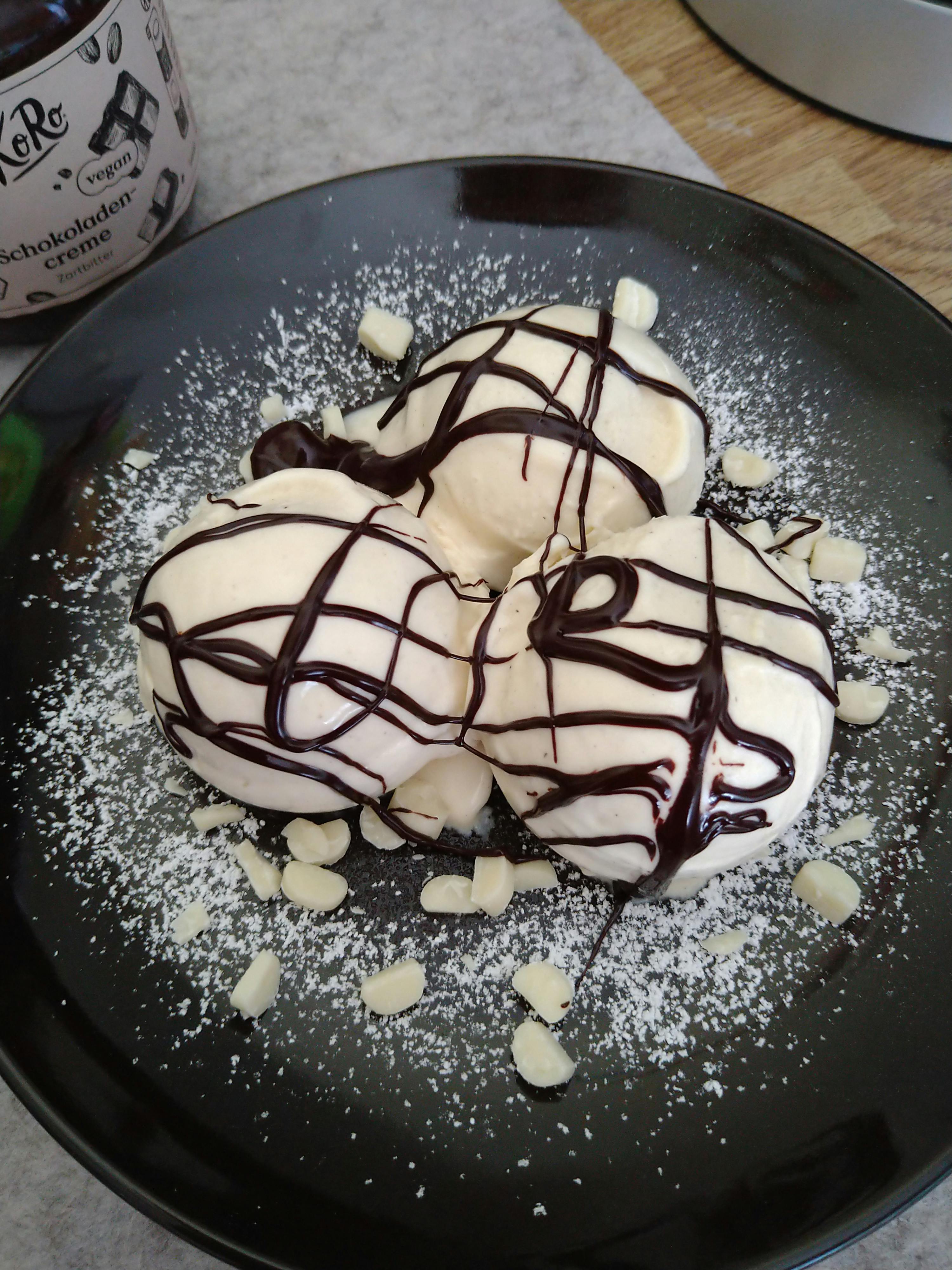 un piatto nero con due gelati e una bottiglia di salsa al cioccolato