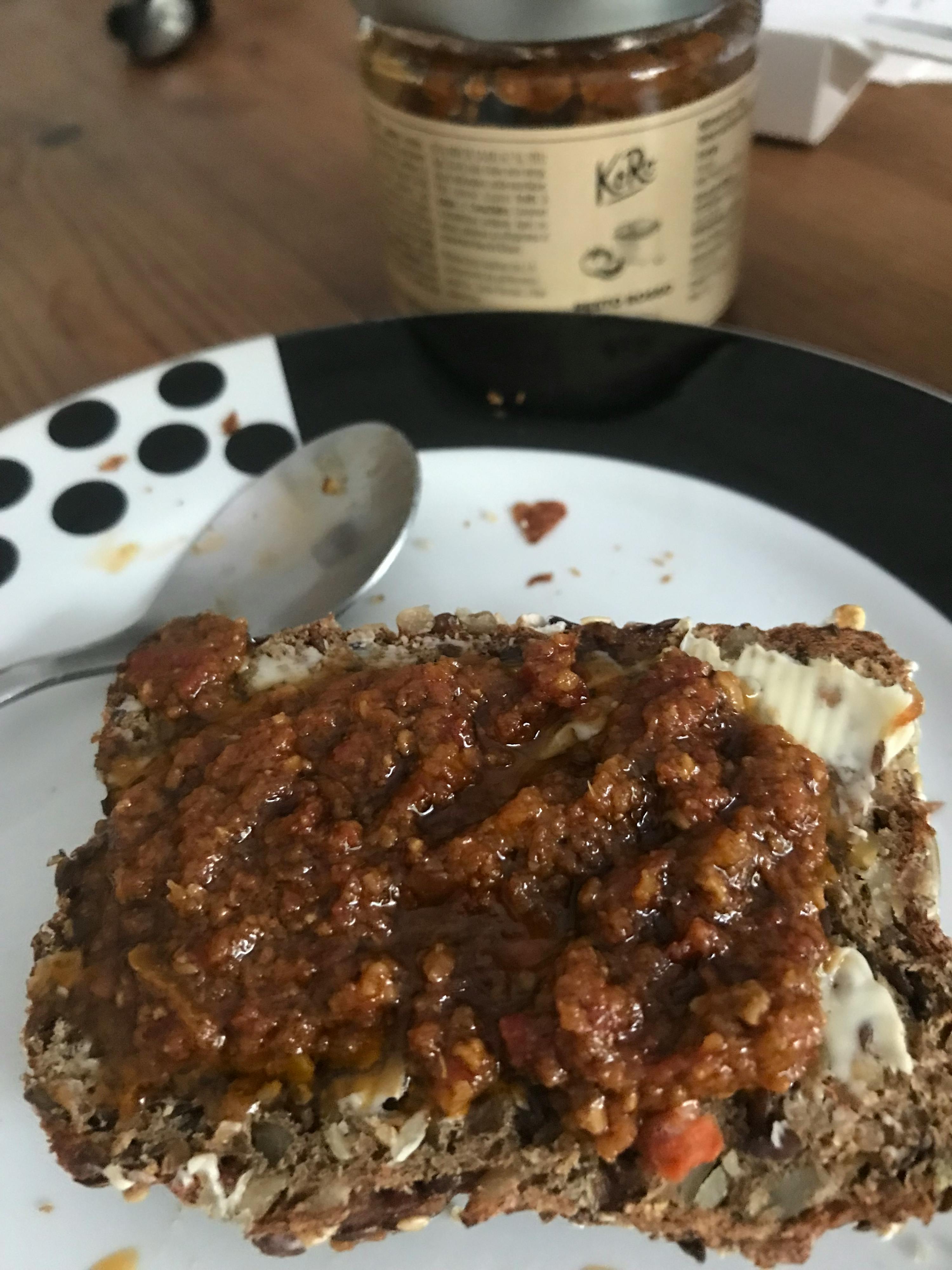 un pezzo di pane con salsa e burro su un piatto accanto a un barattolo di ketchup