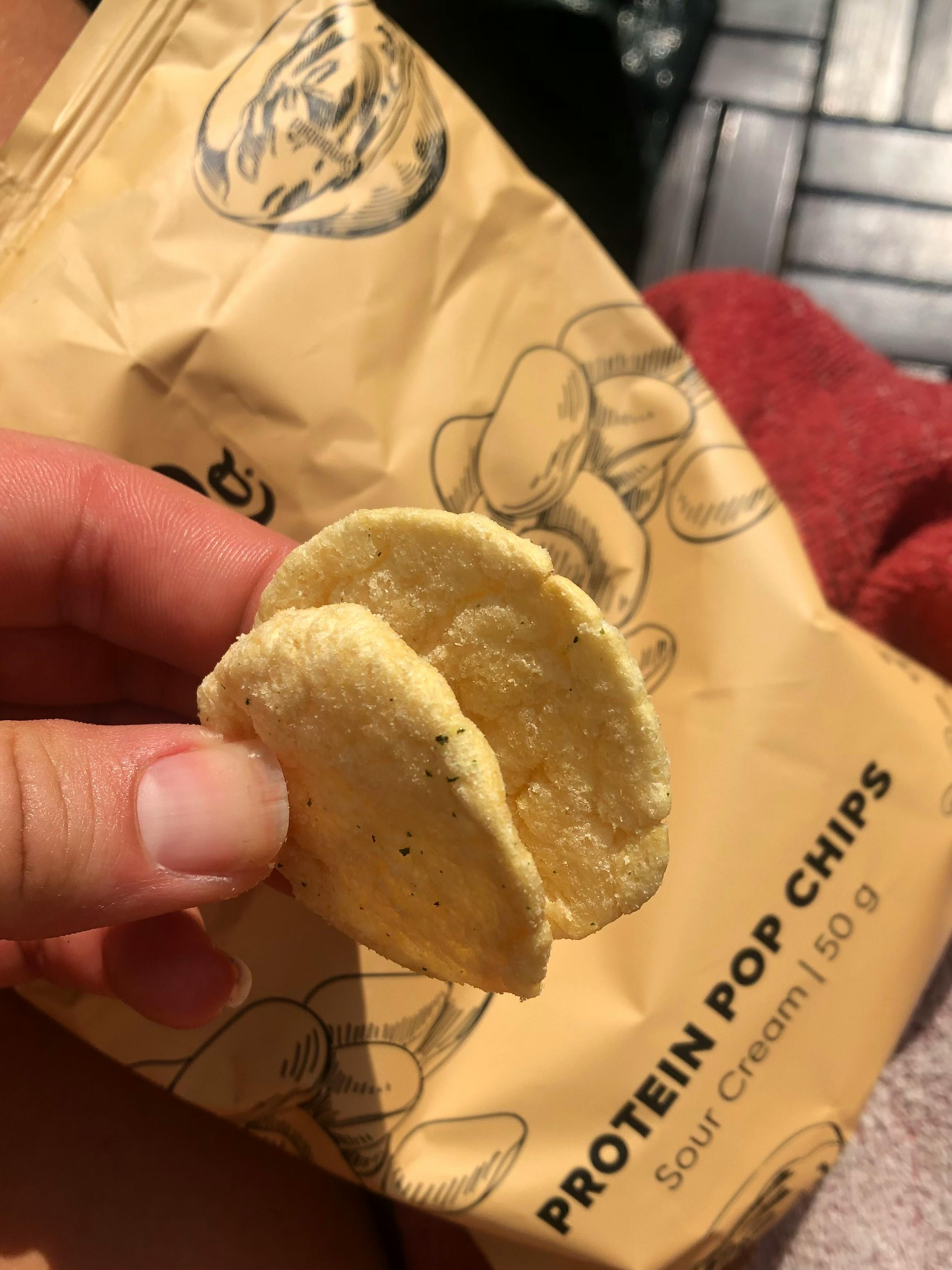 a person is holding a bag of sour cream protein pop chips