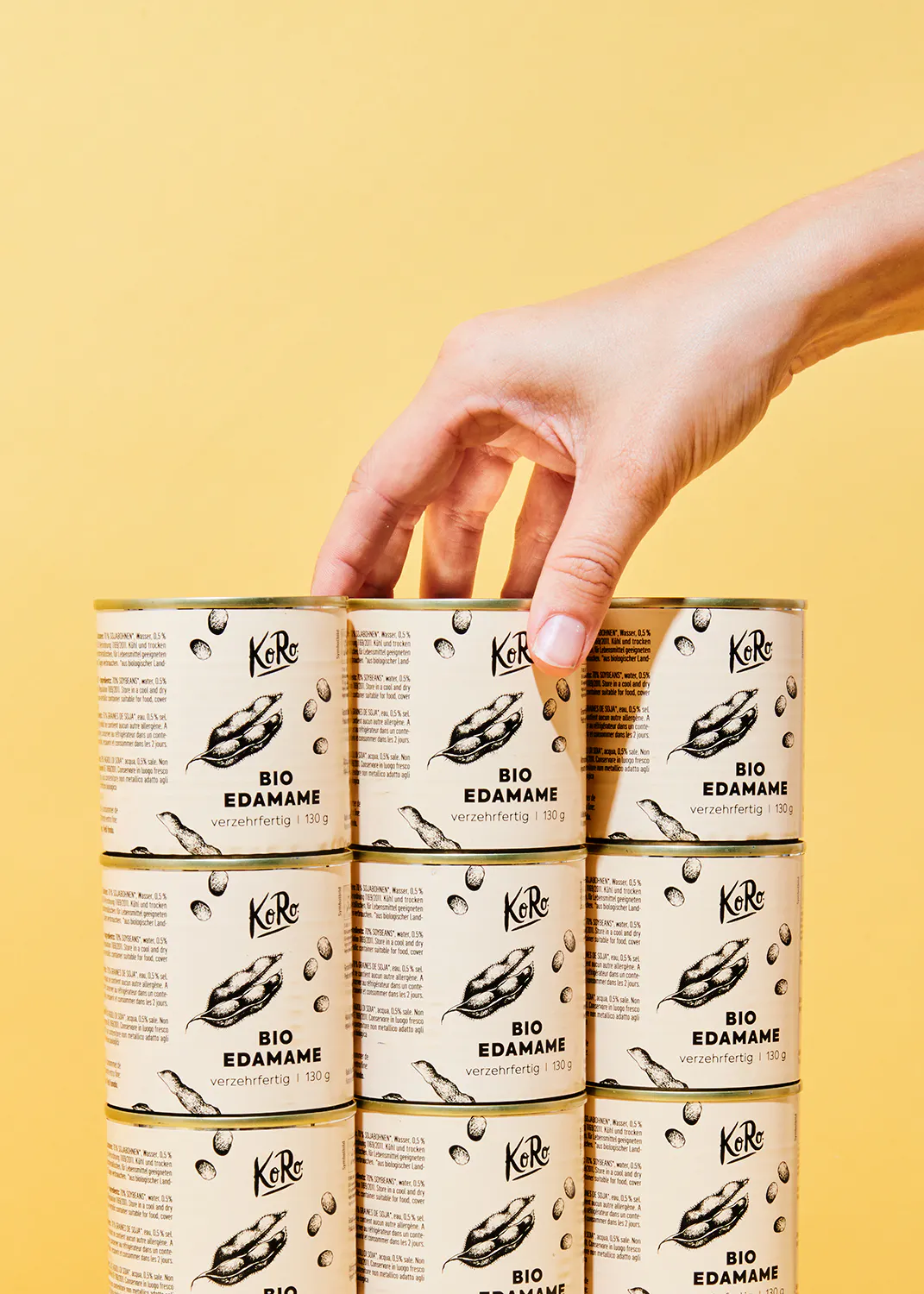 a hand reaches for a can of bio edamame