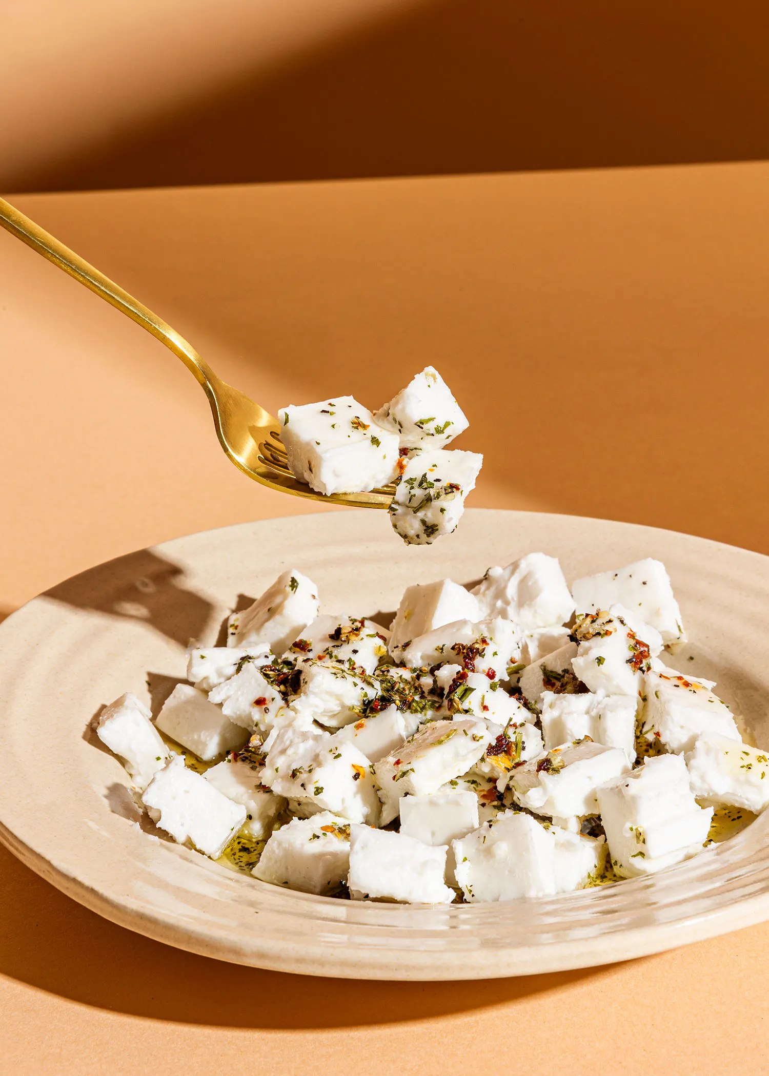 une fourchette tient une tranche de fromage sur une assiette