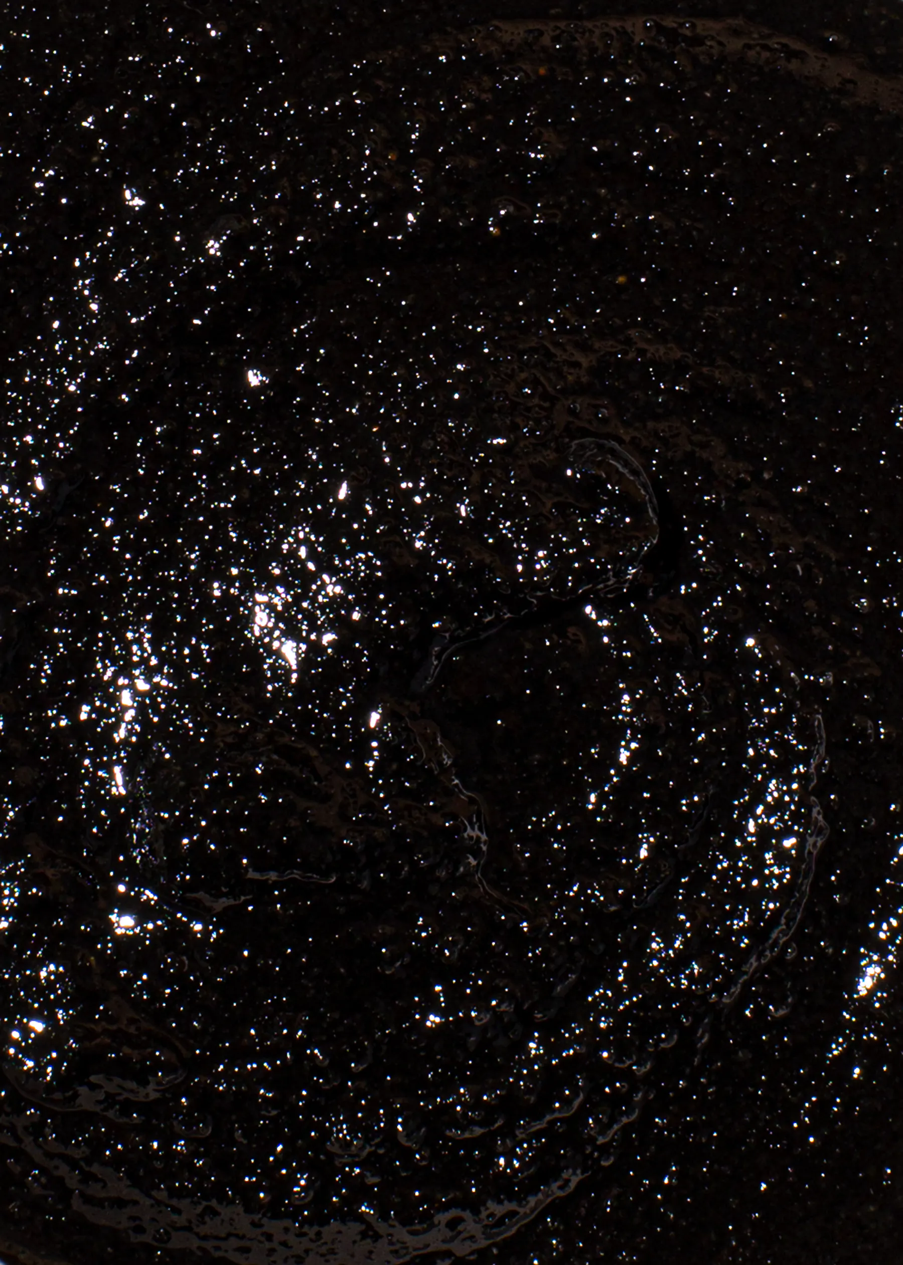 un gros plan d' un liquide noir avec des gouttes blanches