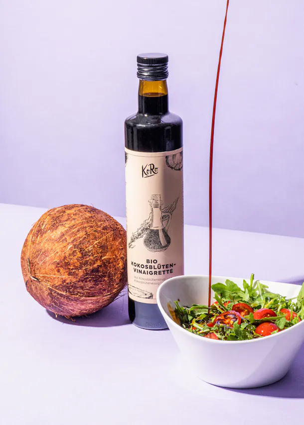 une bouteille de vinaigre de noix de coco est posée à côté d' un bol de salade