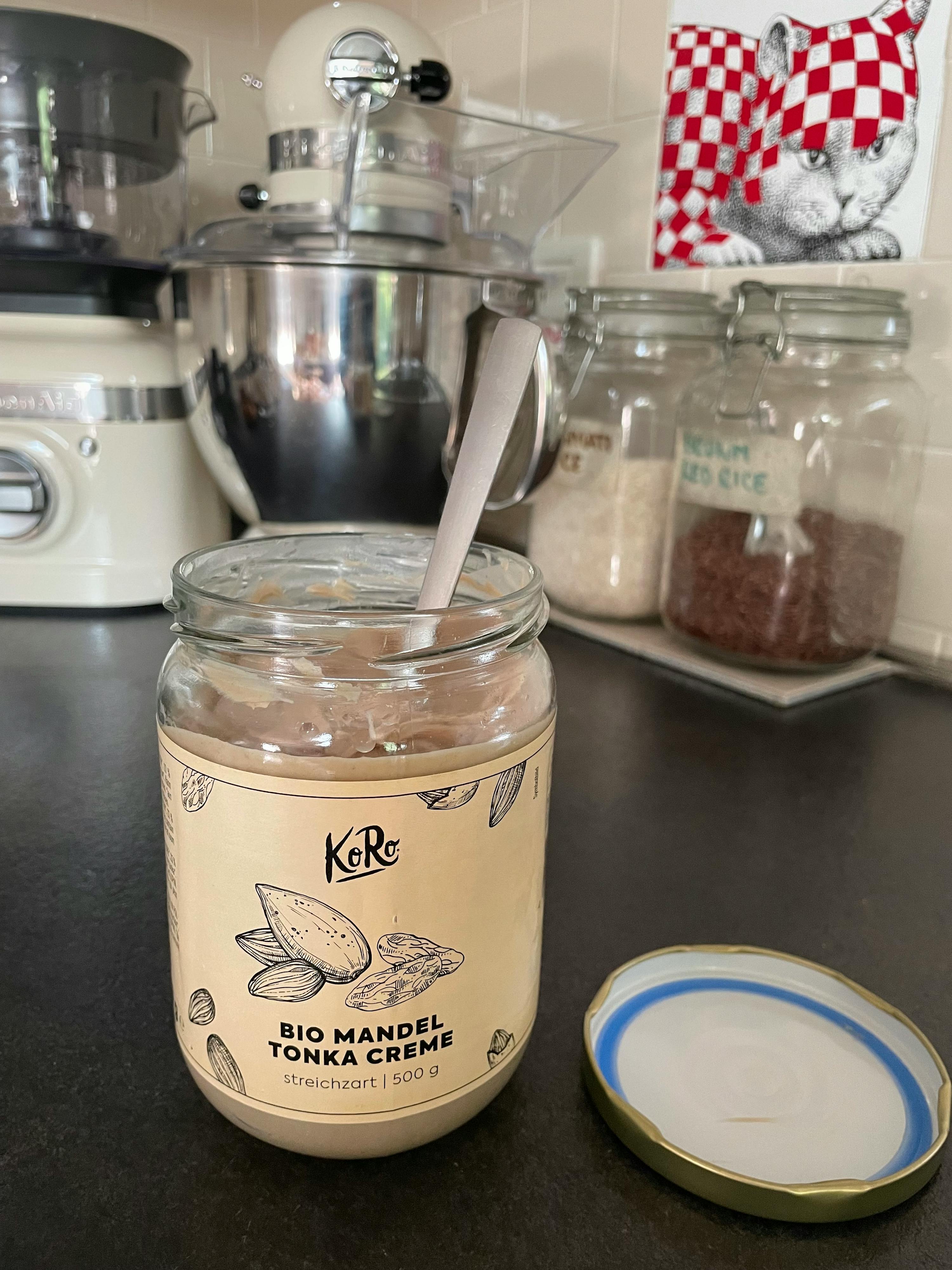 ein Glas bio-Mandel-Tonka-Creme mit einem Löffel darin