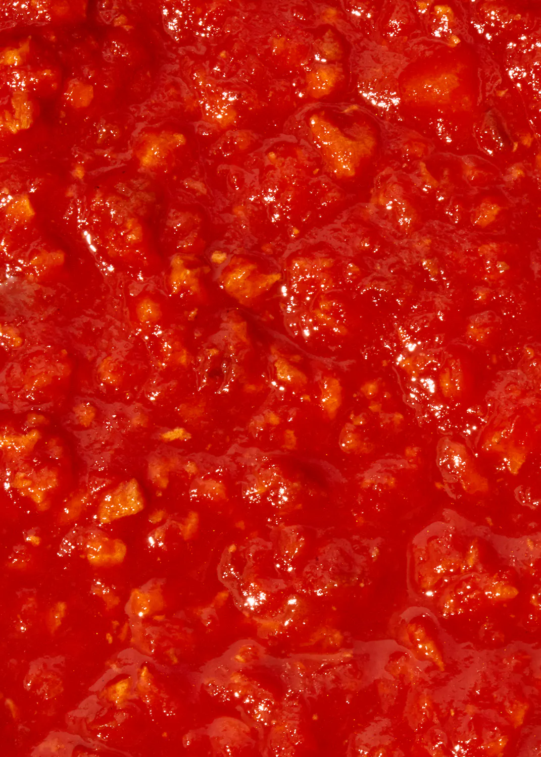 un gros plan d' une sauce rouge avec des morceaux de viande