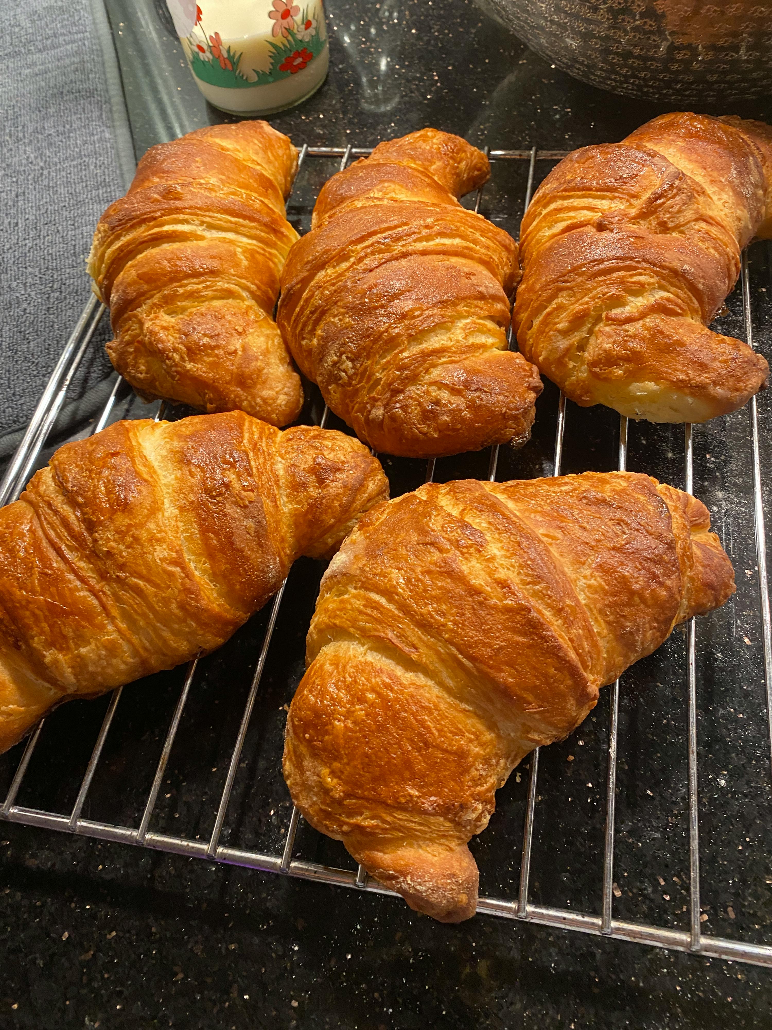 four croissants are sitting on a cooling rack on a counter