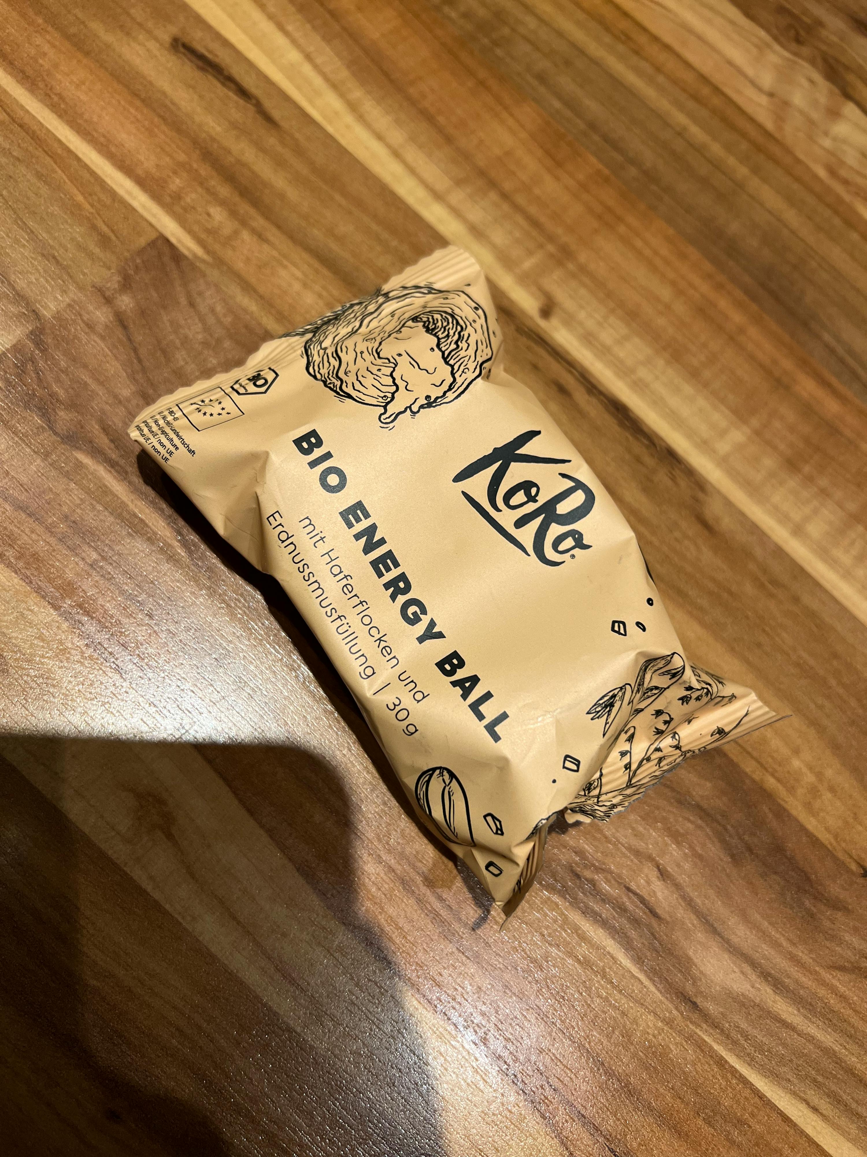 eine verpackte Bio-Energiekugel liegt auf einem hölzernen Tisch