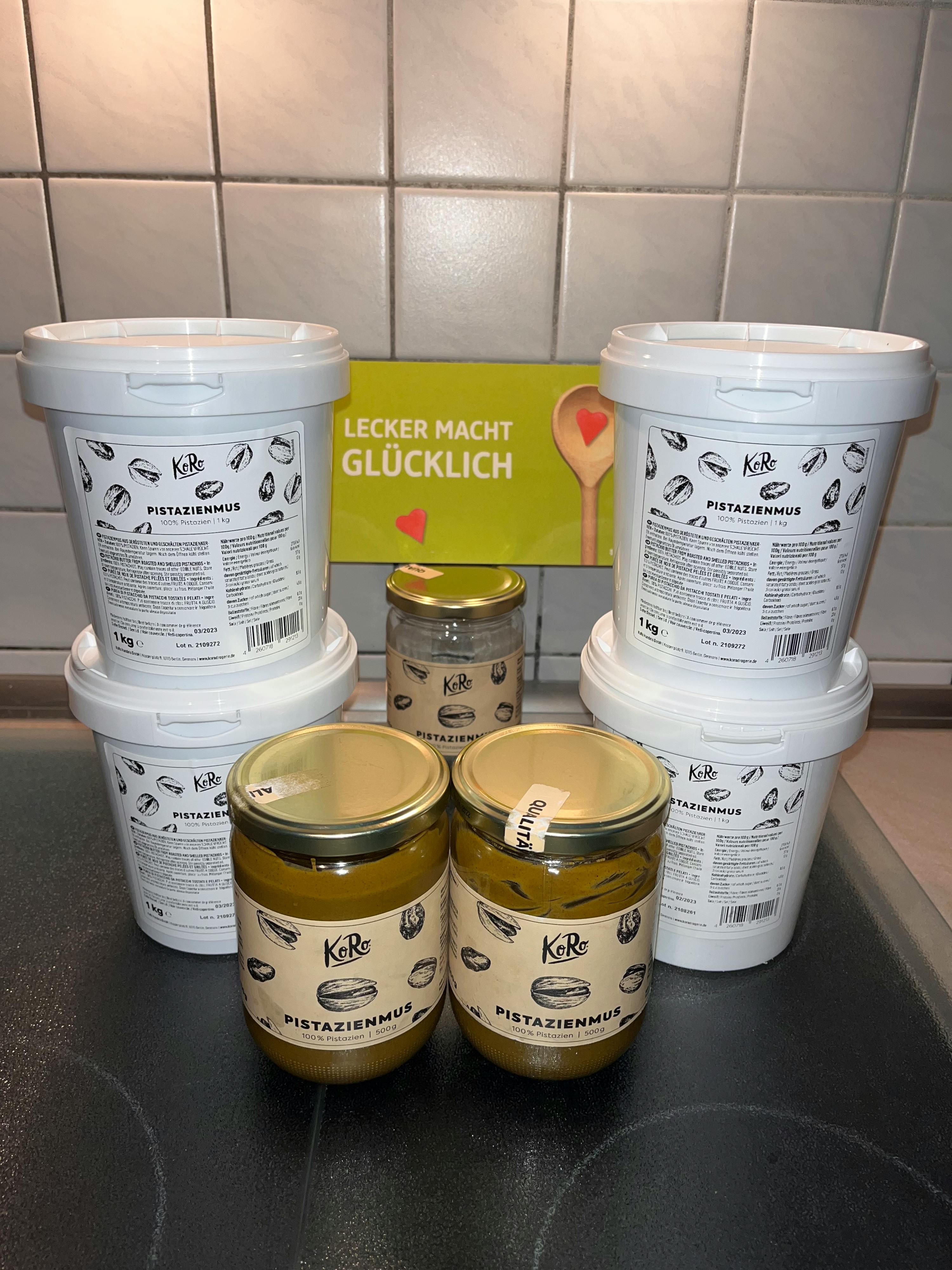 quatre pots de pate de pistache sont empilés sur un comptoir