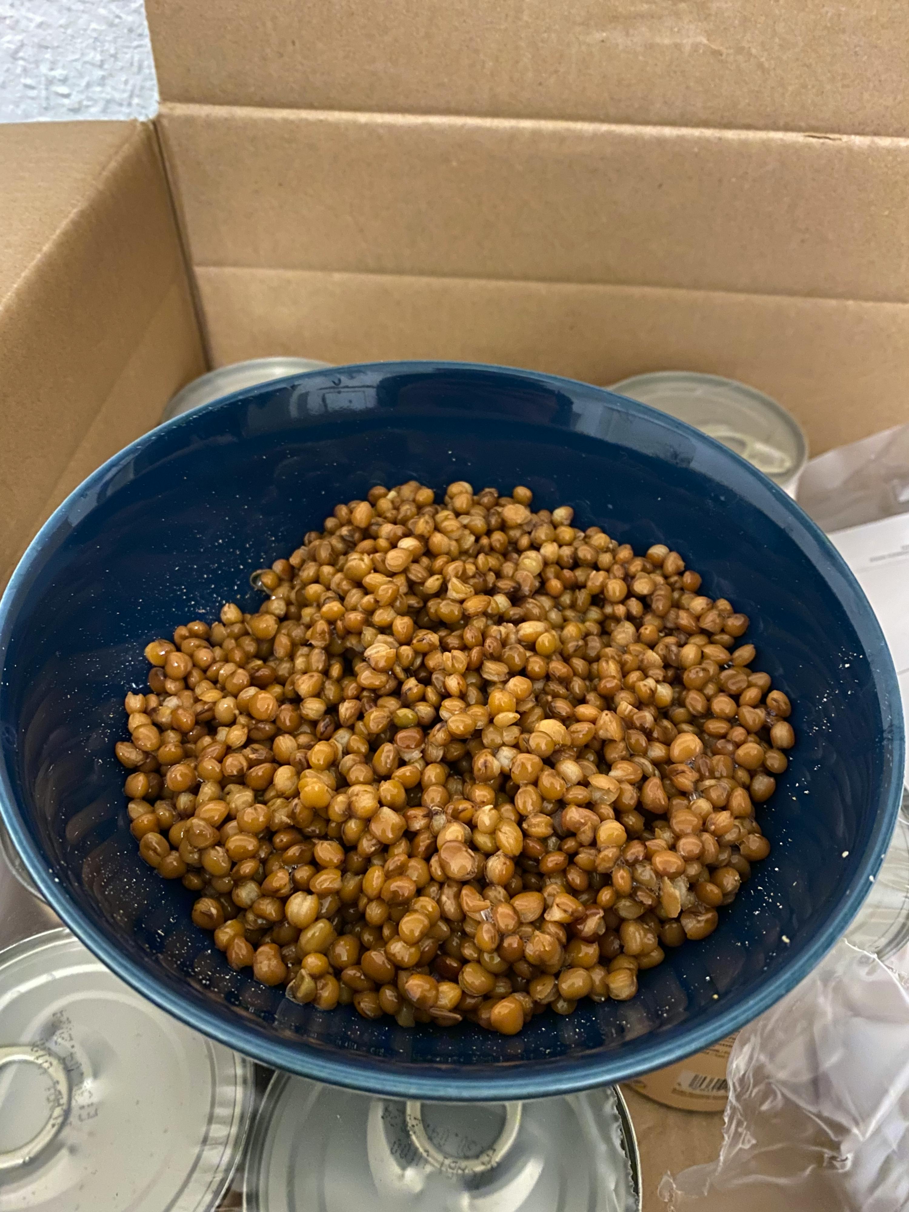 a blue bowl filled with chickpeas sits on top of a cardboard box