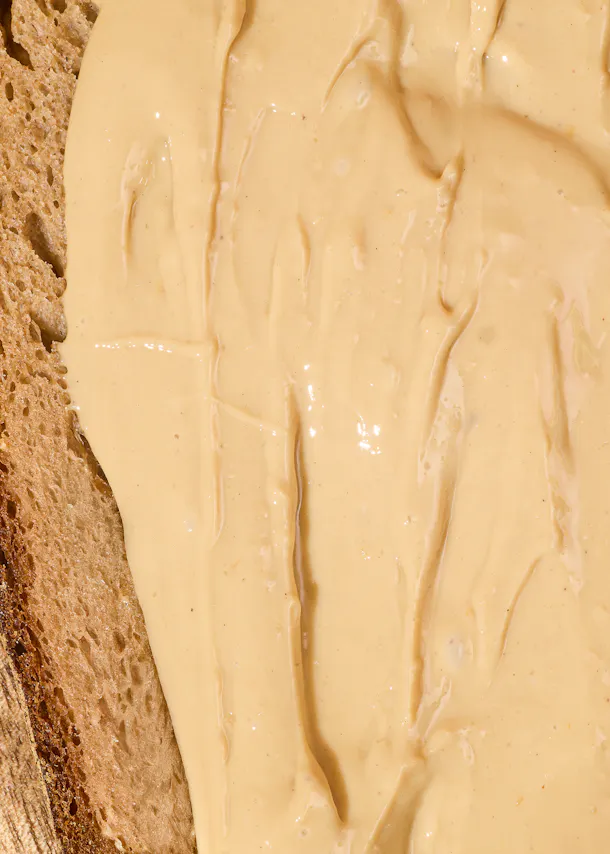 une tranche de pain est couverte de beurre d' arachide