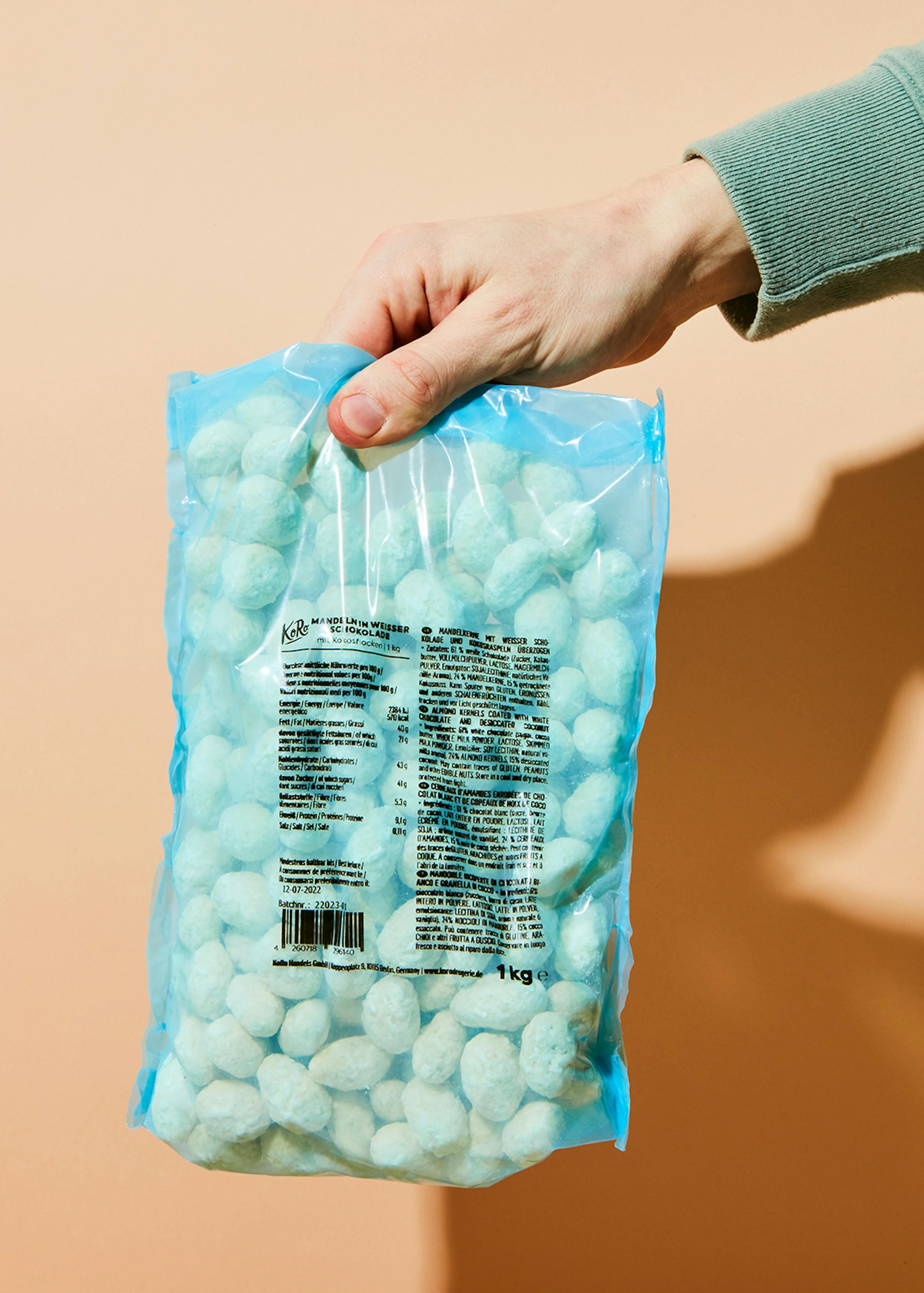 eine Person hält einen blauen Plastikbeutel mit weißen Süßigkeiten in der Hand