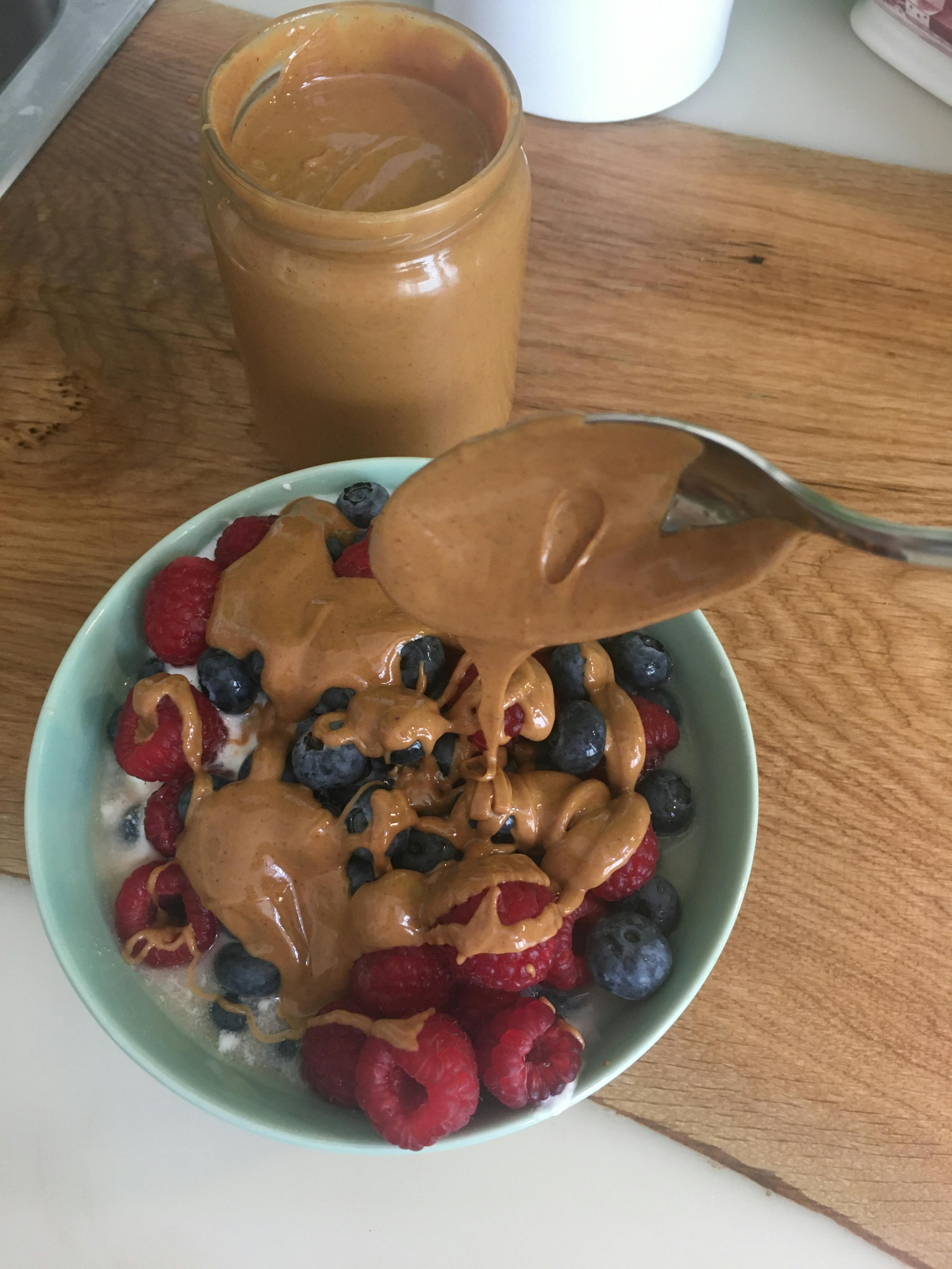 a bowl of yogurt with raspberries blueberries and peanut butter